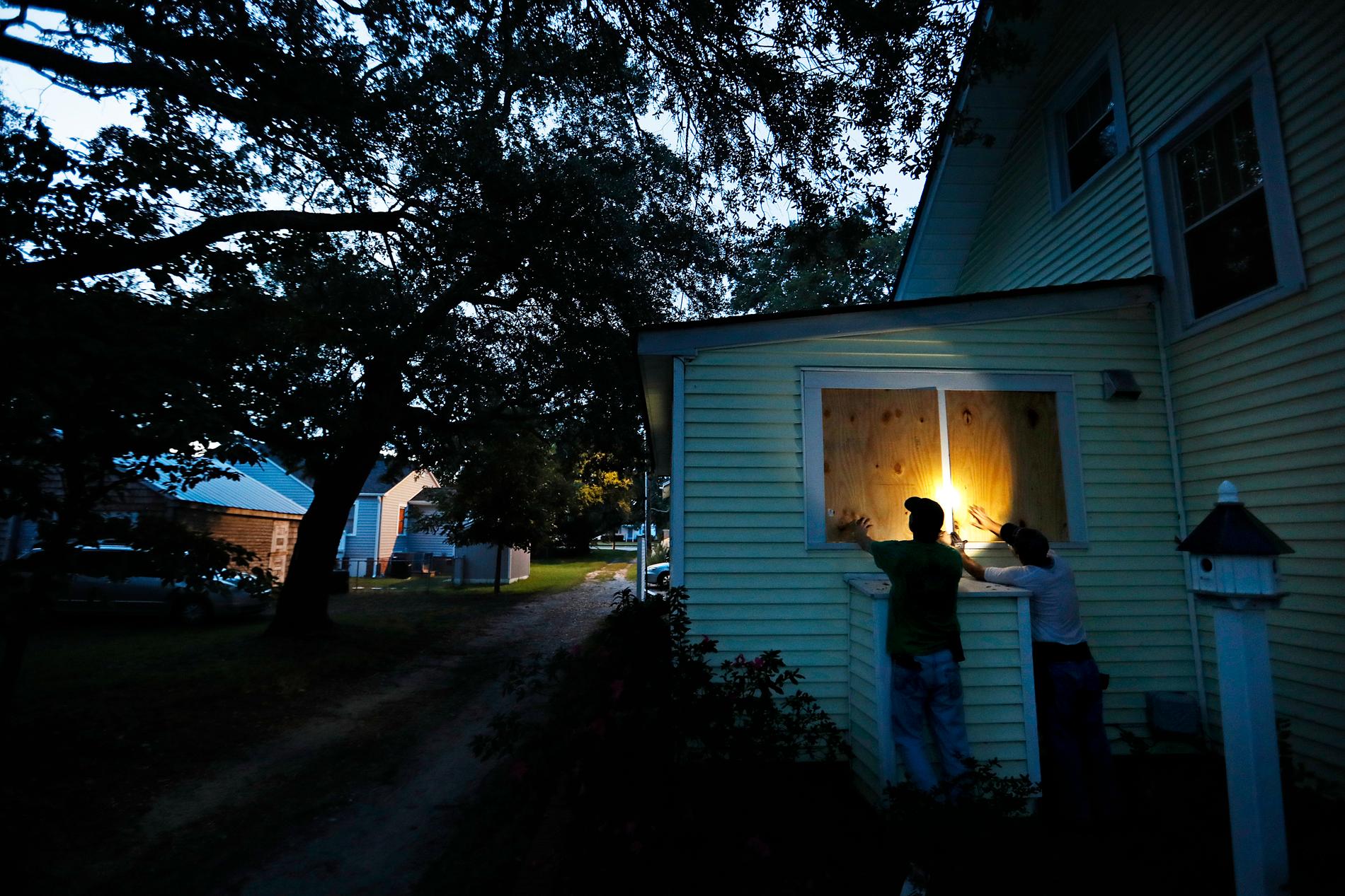 Grannarna Russell Meadows och Rob Muller hjälps åt att spika igen fönster i North Carolina inför "Florence".