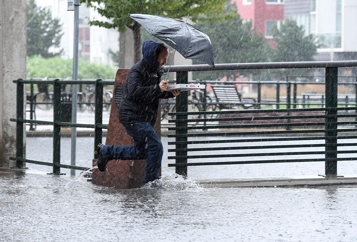 En man i Malmö skyddar pizzan under ett paraply. 
