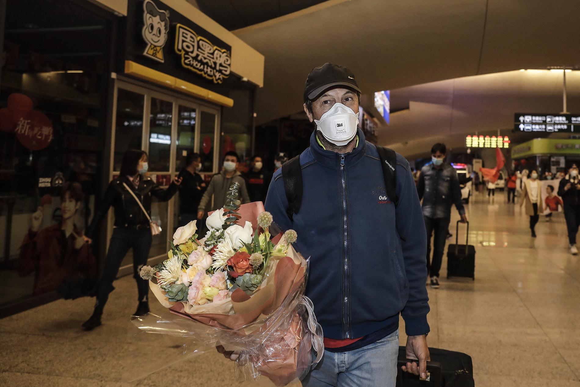 Tränaren Jose Gonzalez välkomnas hem med blommor på Wuhans tågstation.