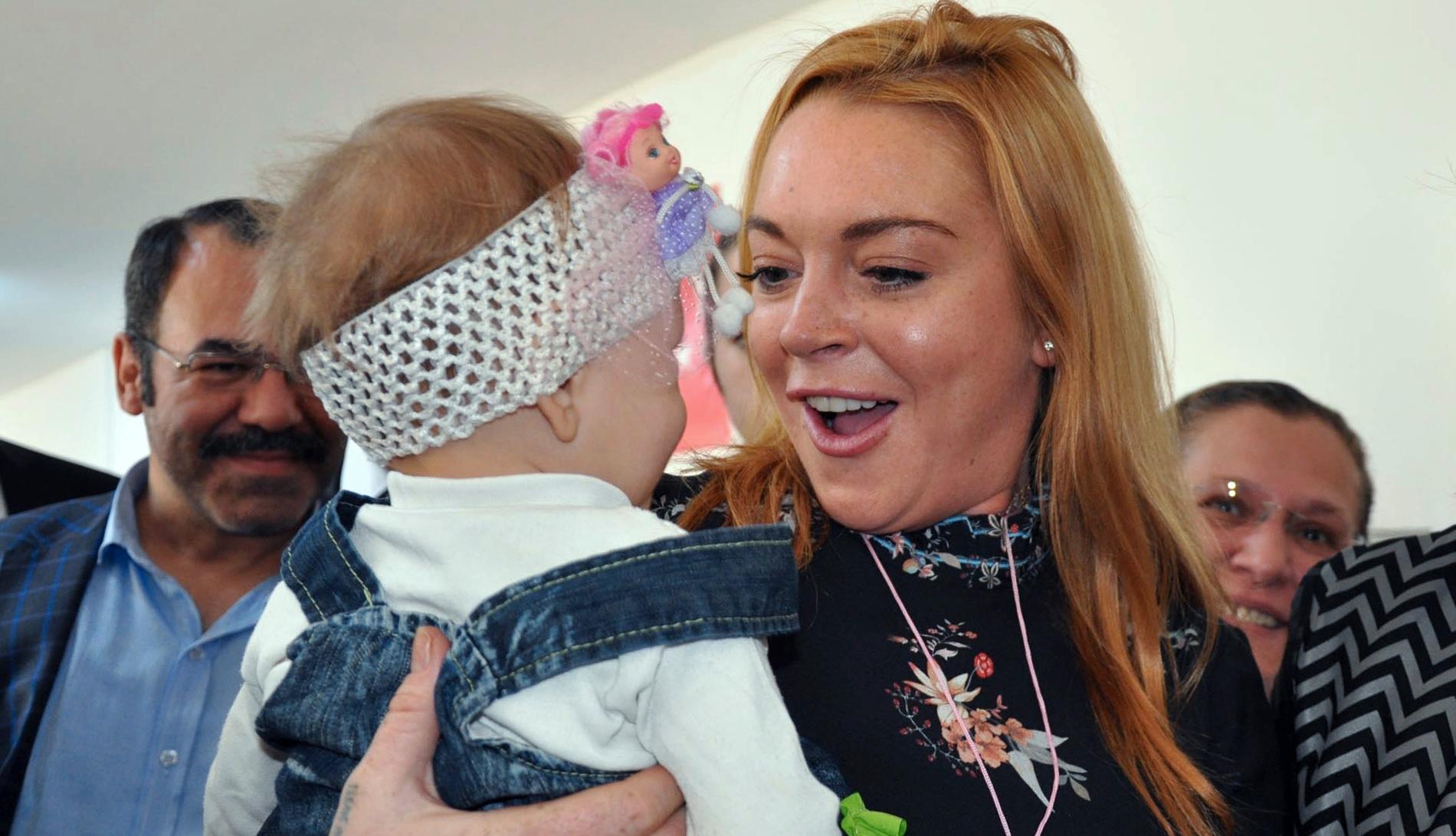 Lindsay Lohan bär ett flyktingbarn från Syrien, under ett besök på en statligt flyktingförläggning i Turkiet.