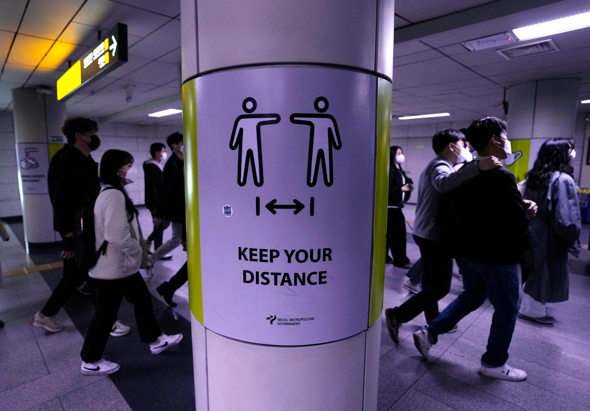 Människor med munskydd på en tunnelbanestation i Seoul uppmanas hålla avstånd.