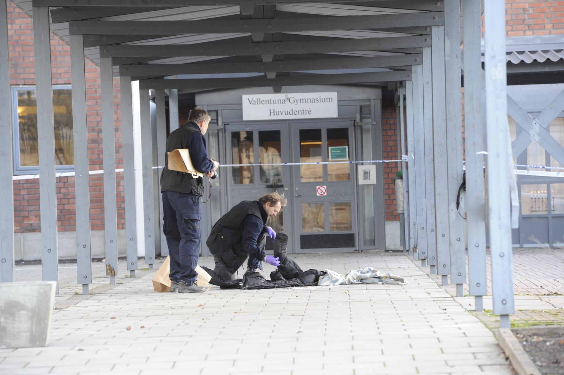 Polisens tekniker undersöker en hög med kläder som ligger på platsen för knivdådet.