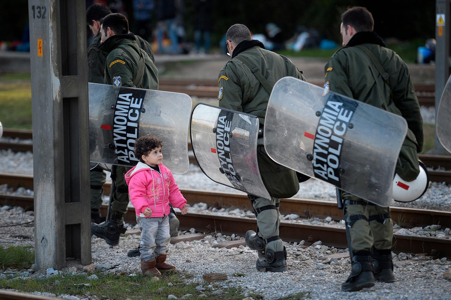 Rayenna Haj Khalaf, 3 år tittar upp mot den grekiska polisen som passerar lägret vid gränsen mellan Grekland och Makedonien där hon bor för tillfället.