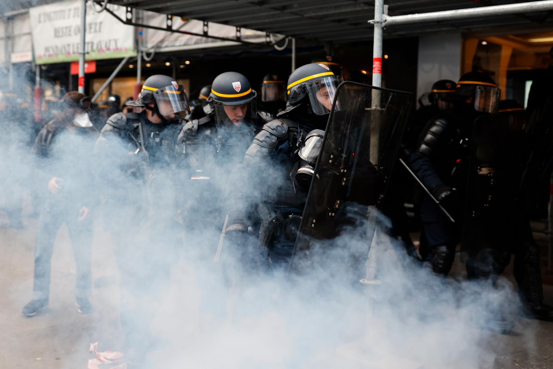 Kravallpoliser skyddar bland tårgas under.