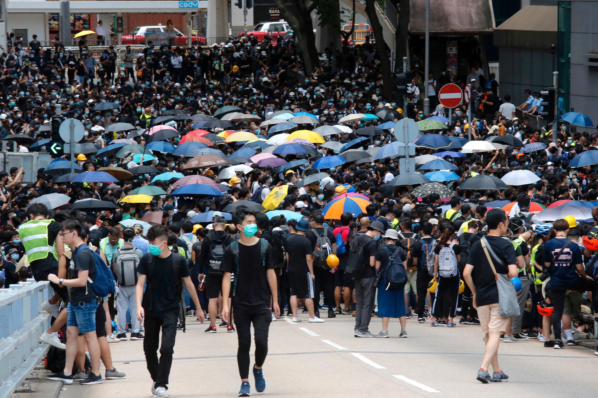Svartklädda demonstranter har tågat genom delar av Hongkong och samlats vid polisens huvudkontor under fredagen.