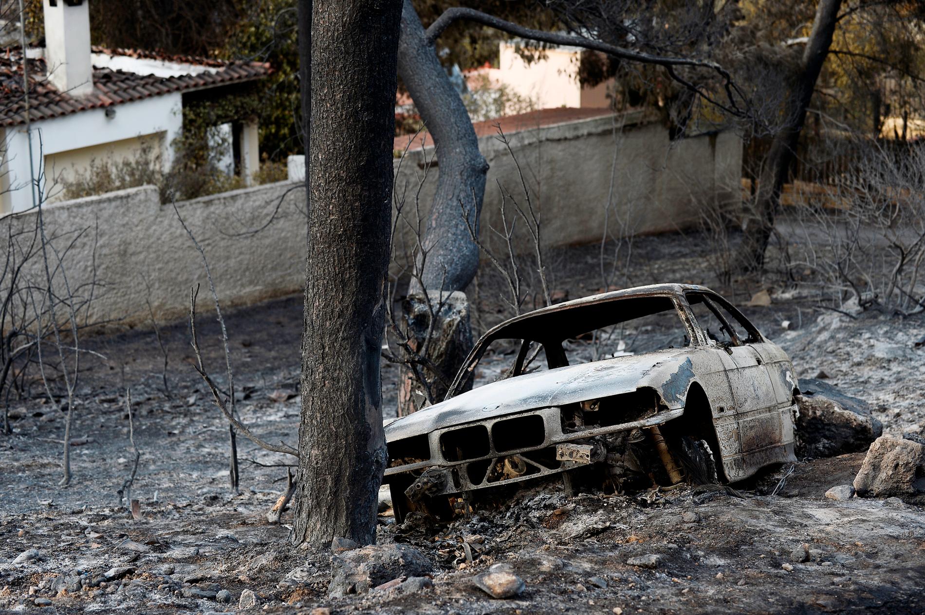 Utanför huset står en urbränd bil mot ett träd. I bilen satt fyra personer – alla dog i bränderna. 