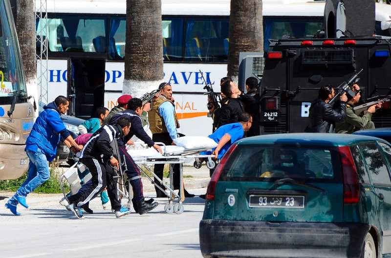 Räddningstjänstens personal eskorteras av säkerhetstjänsten utanför museet i Tunis där massakern ägde rum i onsdags.