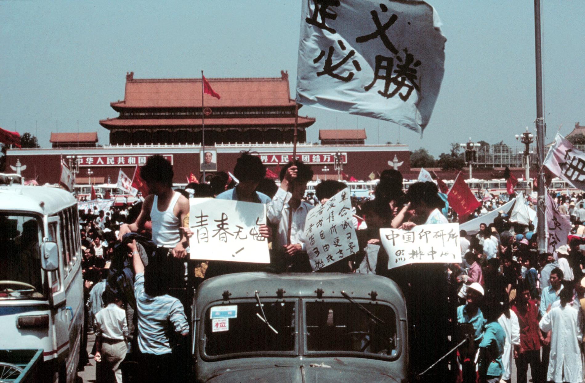 Studenterna står på flaket till en lastbil med flaggor och affischer med slagord.