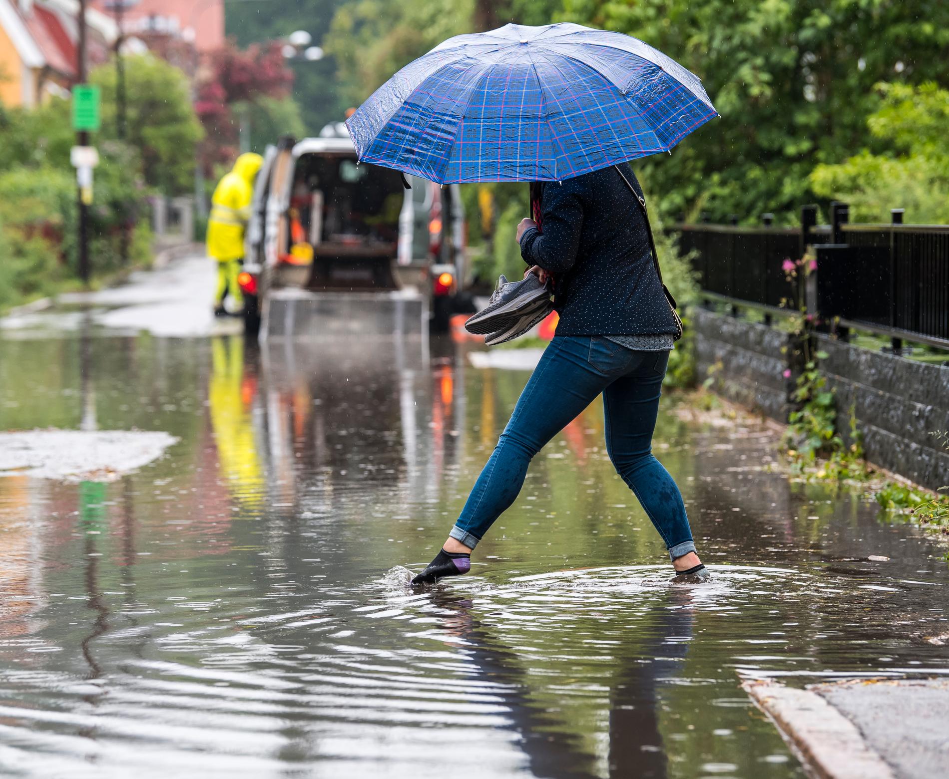 I Enskede i Stockholm vräkte regnet ner och en kvinna tvingades ta av sig skorna och vada fram.