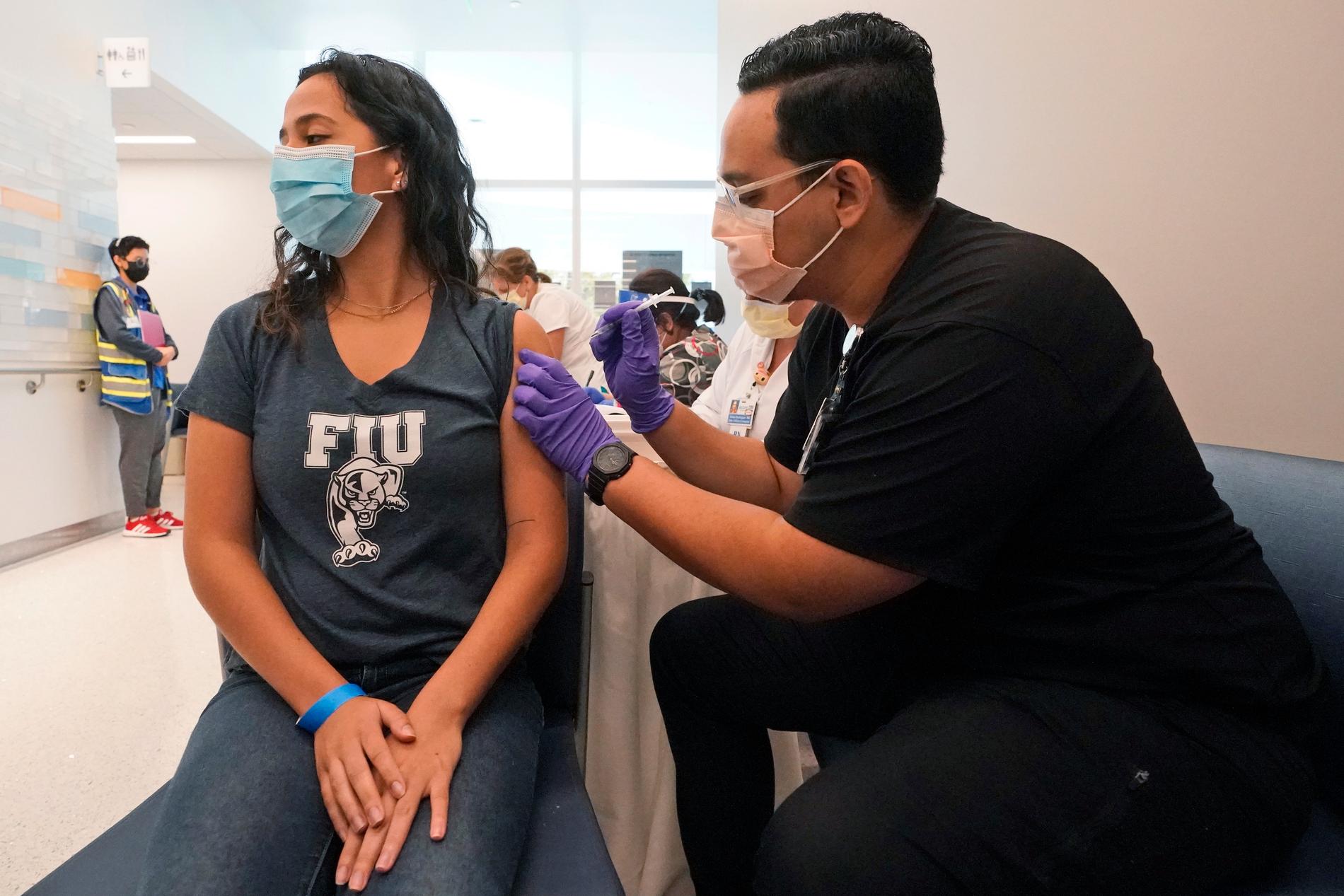 Apotekarstudenten Jason Rodriguez, till höger, ger Camila Gutierrez, en spruta med Pfizers vaccin mot covid-19. Båda studerar vid Florida International University.