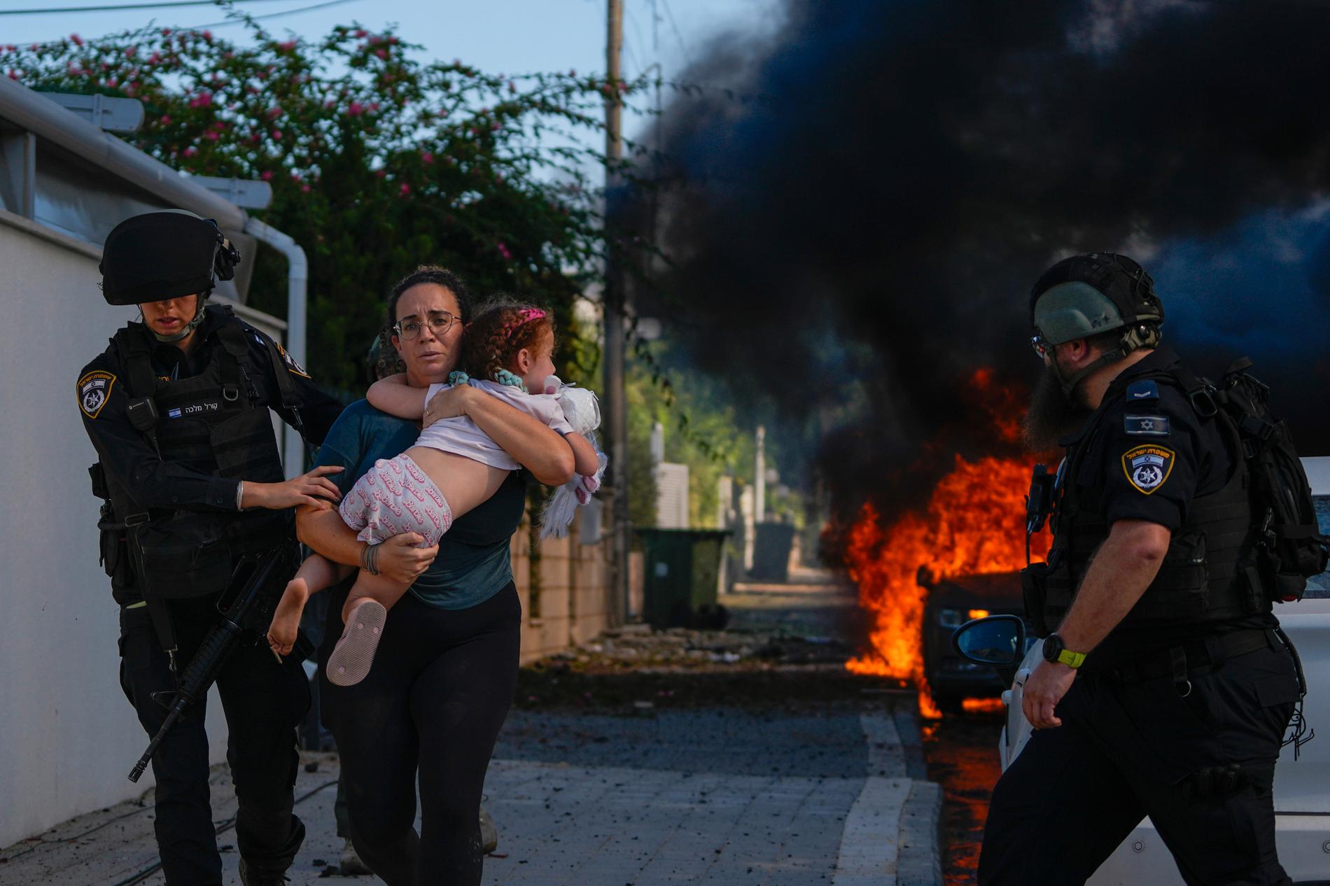 En kvinna flyr med sitt barn efter en raketattack i Ashkelon i södra Israel.