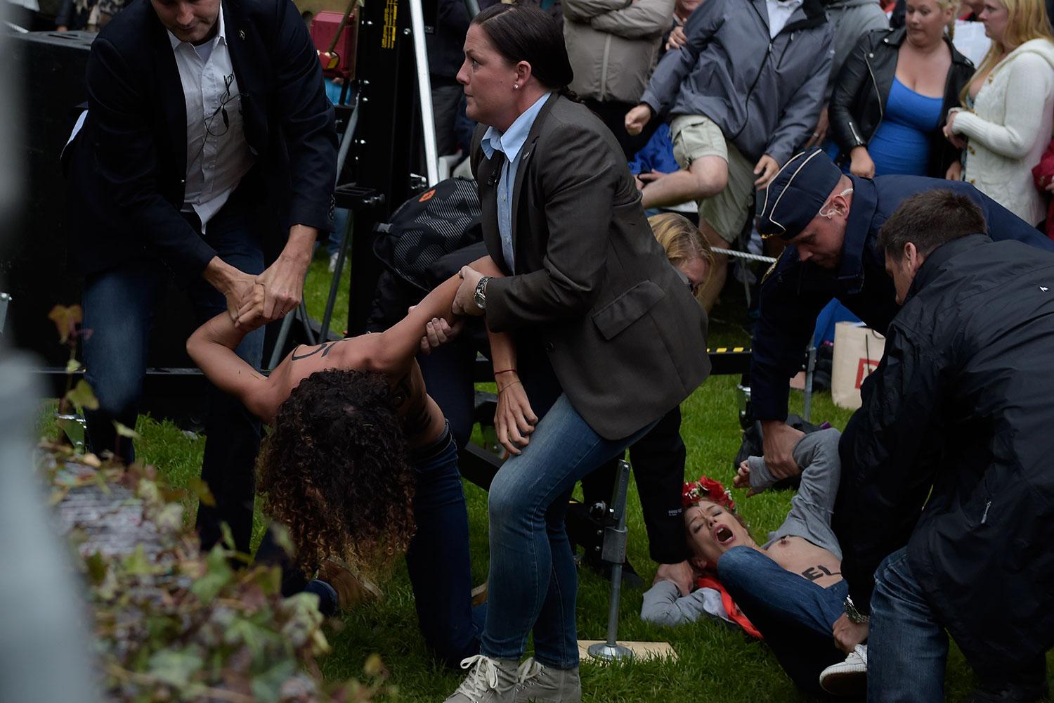 Femen-aktivister brottas ner av polis.
