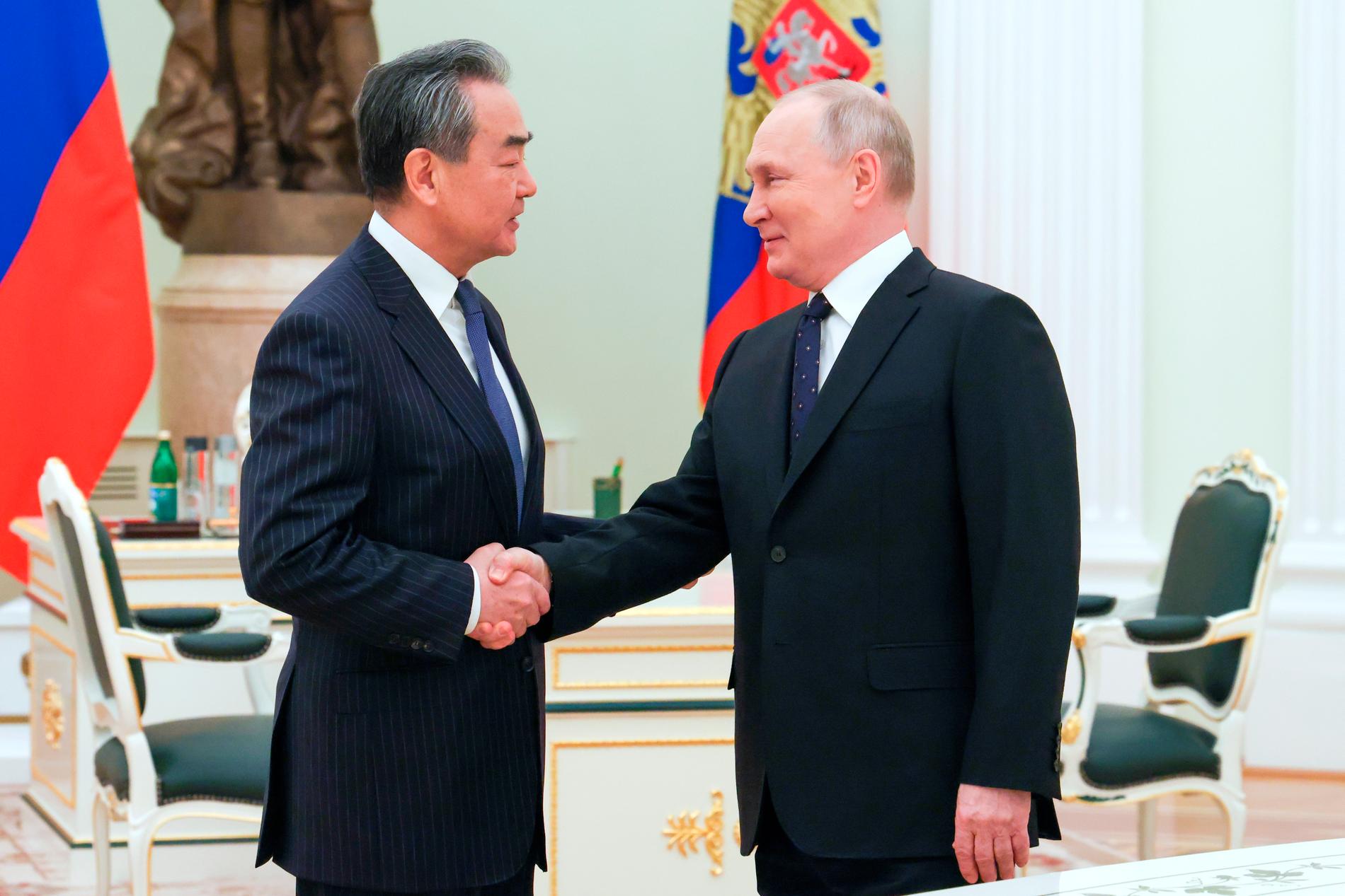 Putin och Wang Yi hälsar i Moskva. 