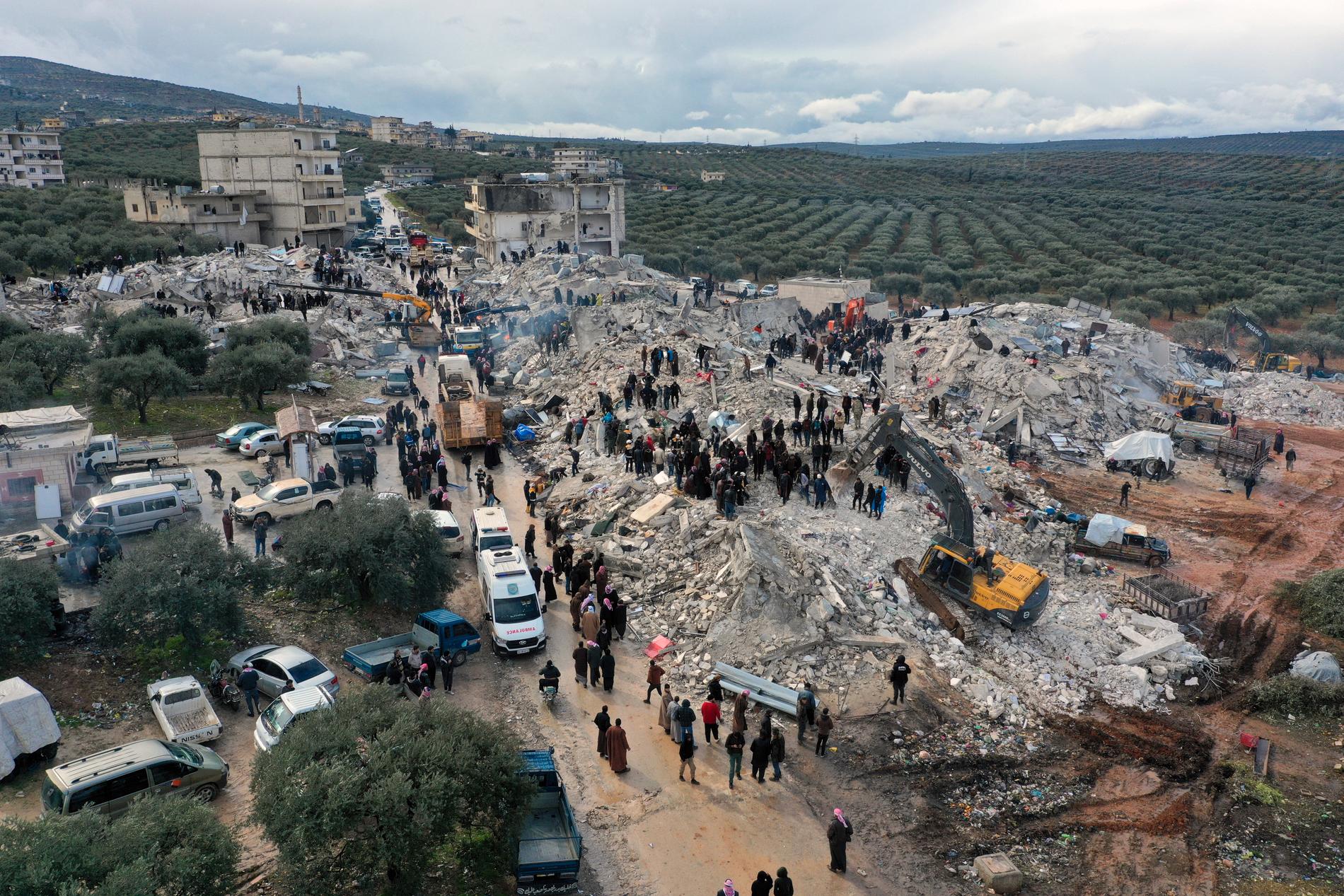 Civilförsvarsarbetare och invånare i staden Harem nära den Turkiska gränsen i Syrien söker igenom spillrorna av kollapsade byggnader efter överlevande.