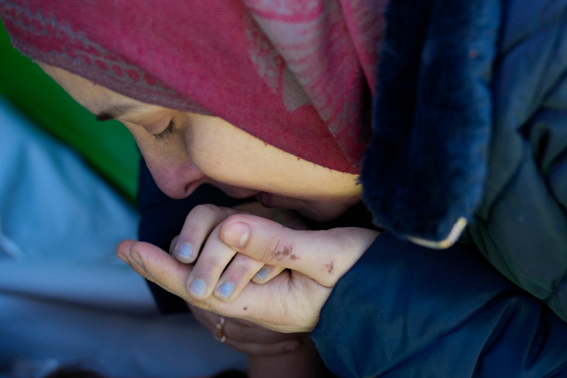 En mamma från Syrien kysser sin döda dotters hand. Totalt tros över 16 000 människor ha dött i Syrien. 