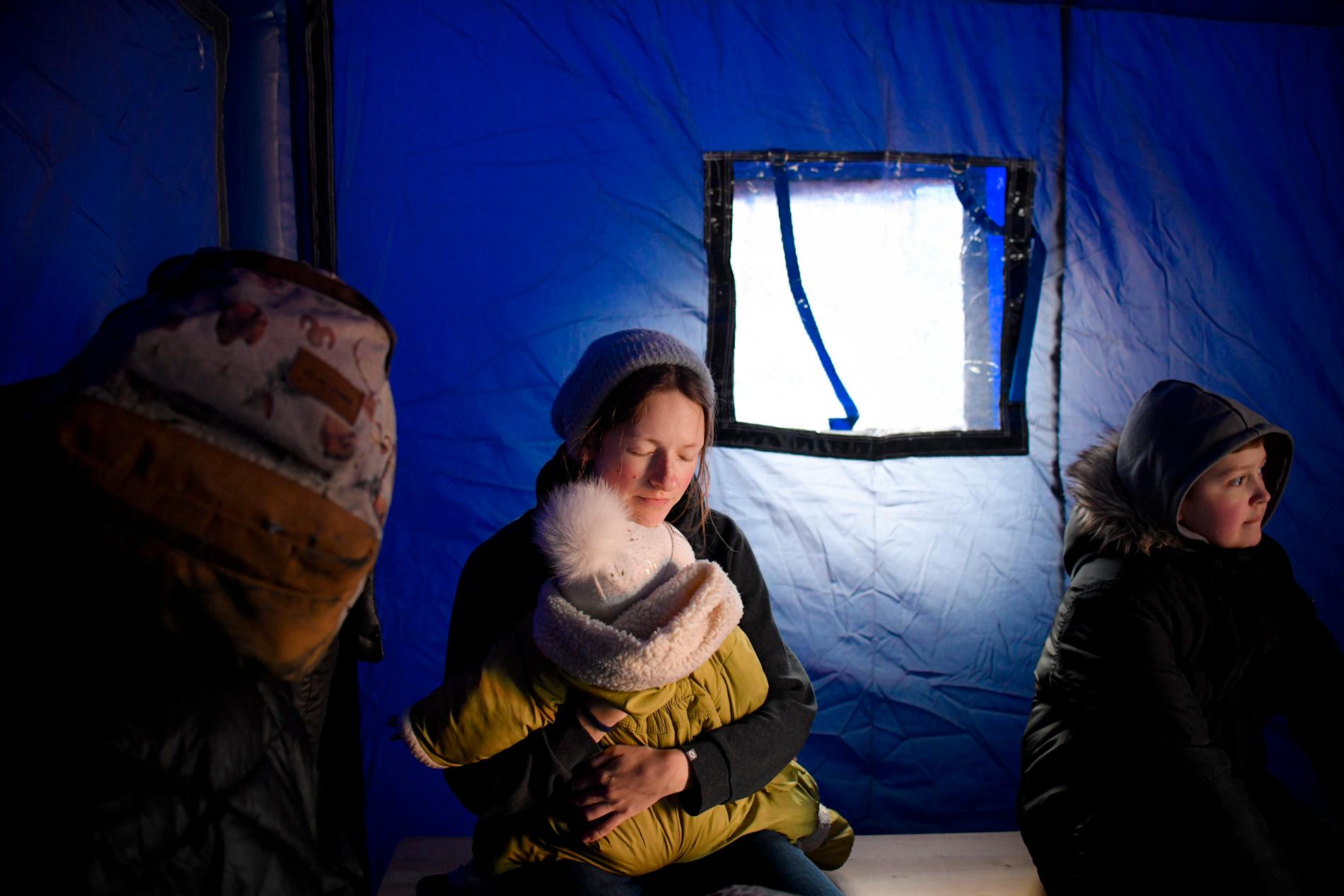 En kvinna på flykt håller om sitt barn i ett tält vid gränsen mellan Ukraina och Rumänien på lördagen. 