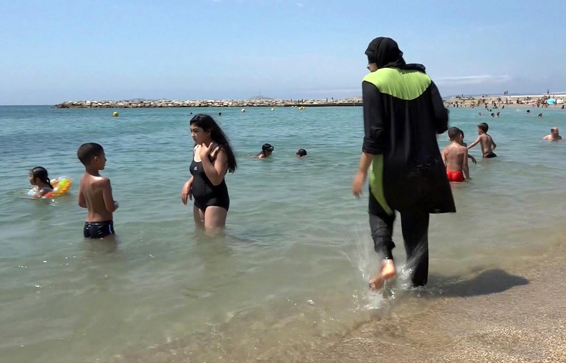 En kvinna på stranden i Marseille som bär burkini, ett badplagg som täcker både huvud och kropp. Arkivbild.