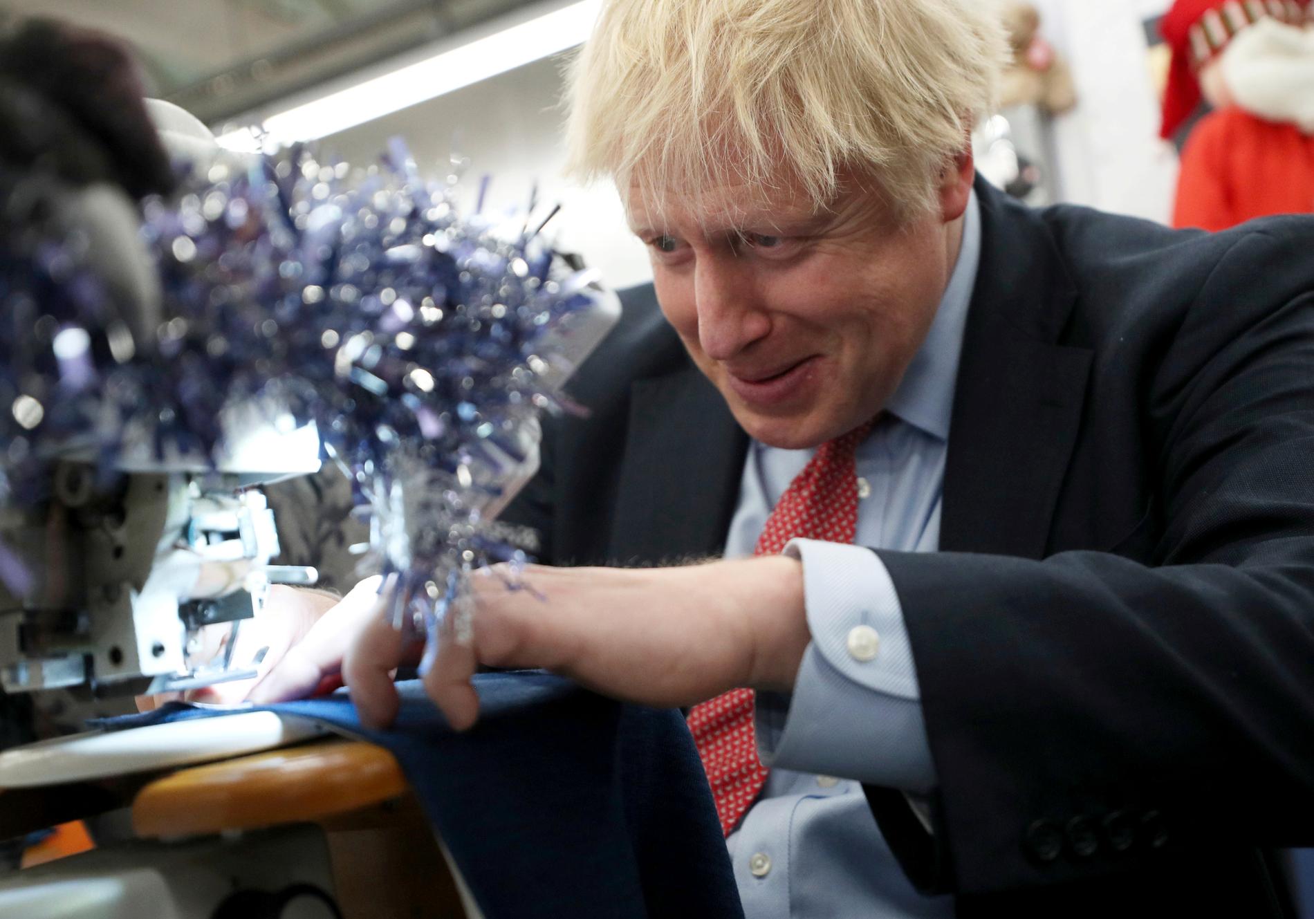 Storbritanniens premiärminister Boris Johnson testar en symaskin under ett valturnéstopp i Matlock i början av december.