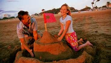 Pelle Svensson med dottern Erika prövar hållfastheten hos ett marockanskt sandslott, naturligtvis utrustat med flagga. "Ren och fin strand, inte en sten", säger Pelle Svensson.