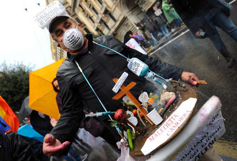 En man bär en miniatyr av en soptipp som han prytt med orden "Jävla Camorra". Han var en av de närmare 100 000 som protesterade mot maffian i går.