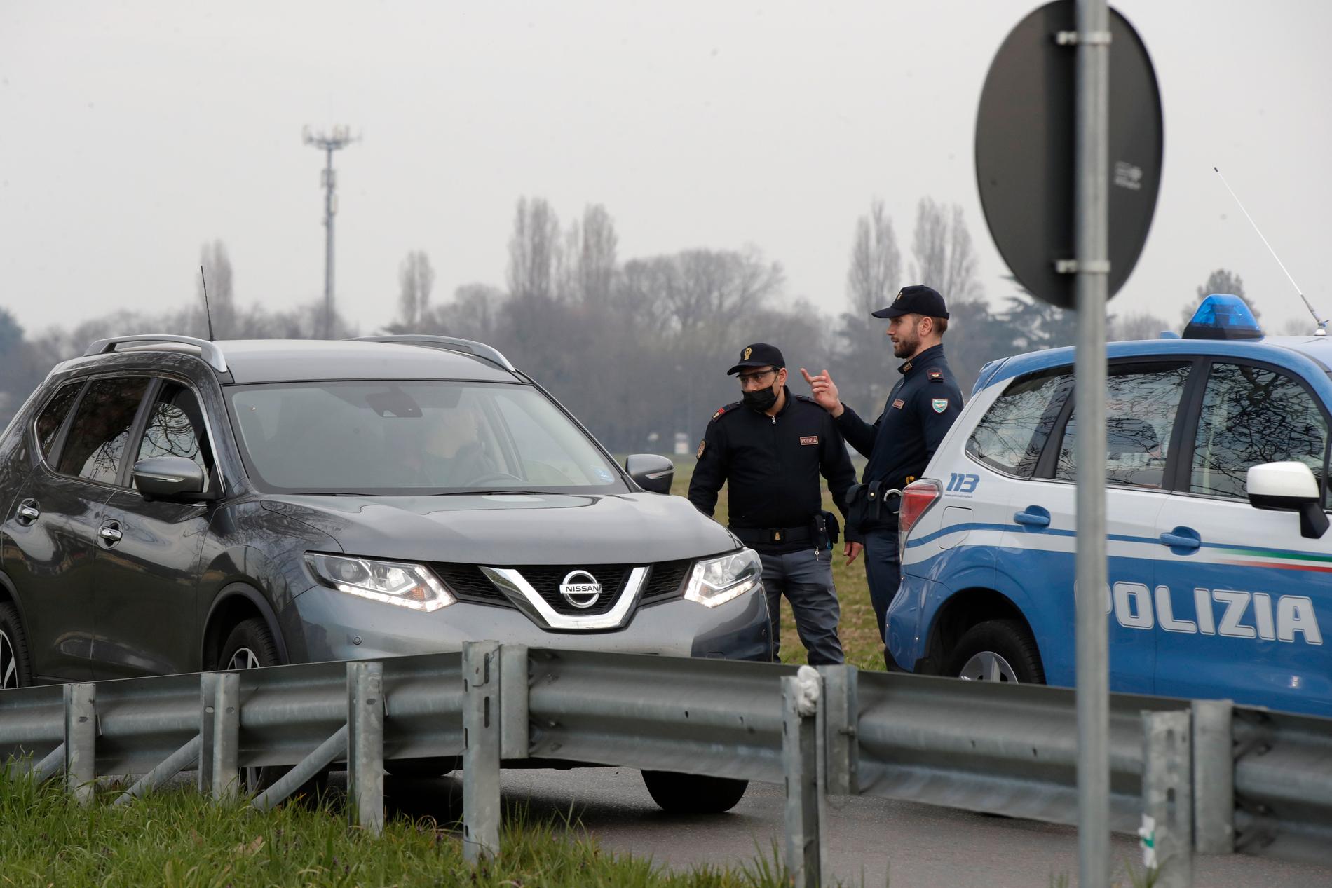 Polis och militär kontrollerar så att inga bilar passerar in i eller ut ur det avspärrade området vid Casalpusterlengo i norra Italien.