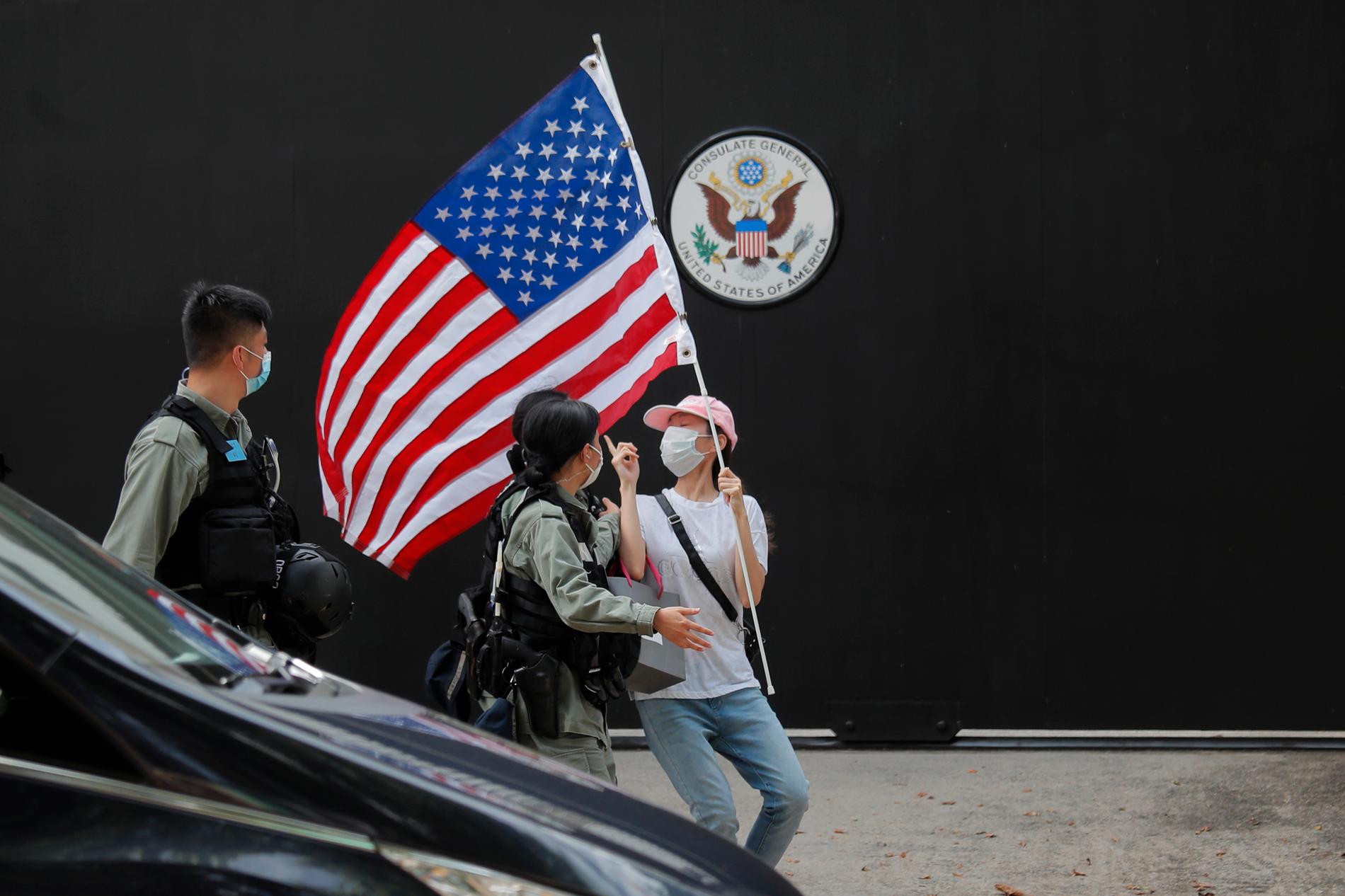En aktivist med en amerikansk flagga motas bort av polis vid en manifestation utanför USA:s konsultat i Hongkong den 4 juli.