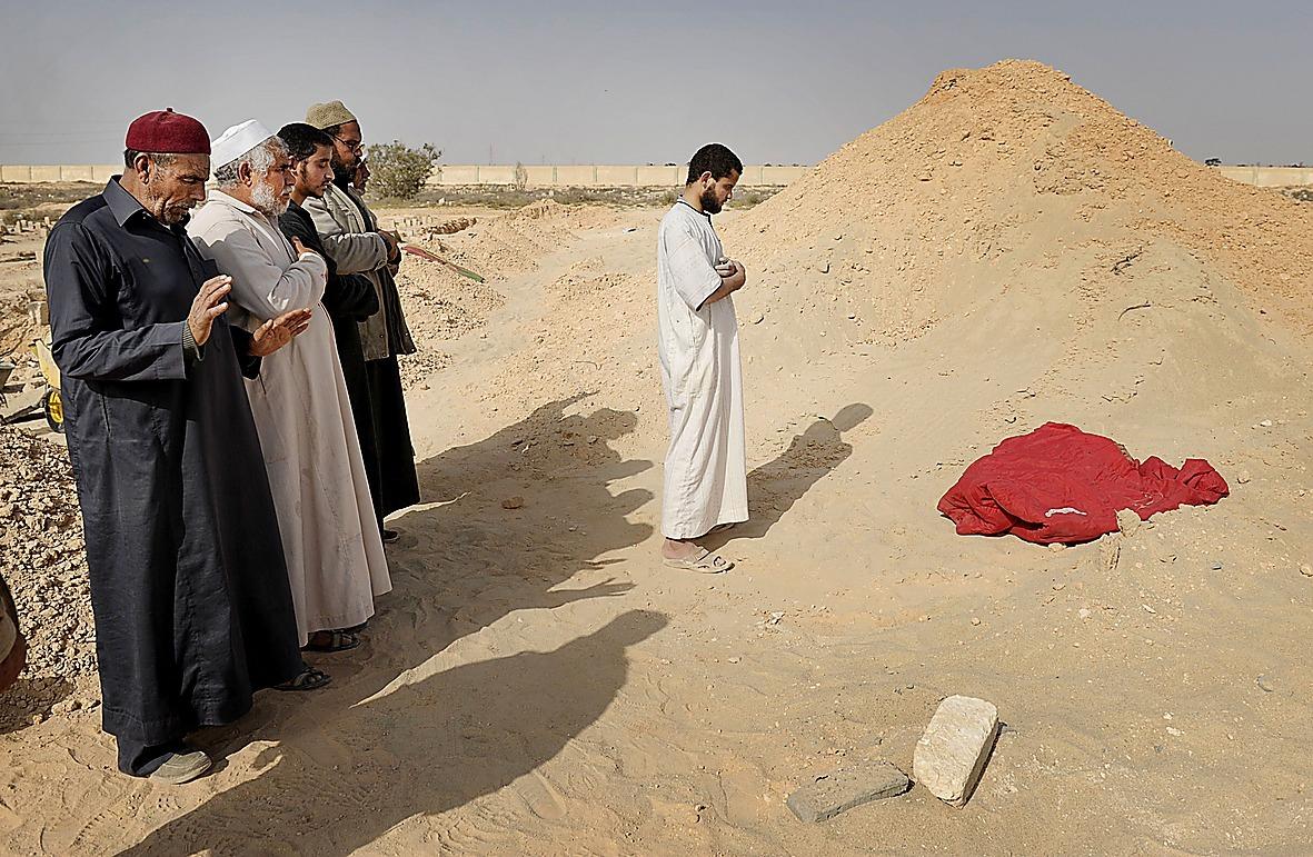 En grupp män begraver en släkting under böner utanför staden.