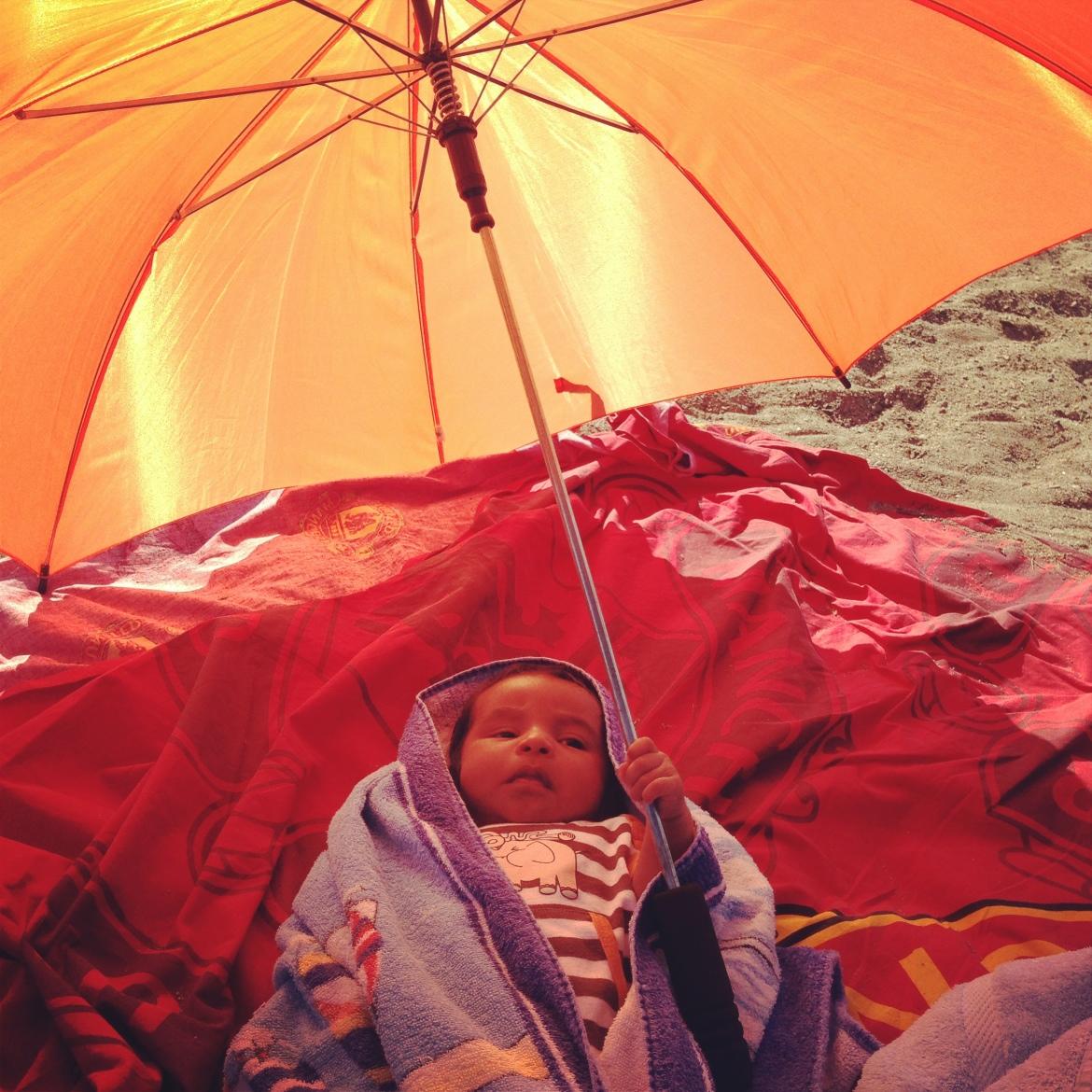 Sonen tog fram paraplyet när det blev varmt på stranden.