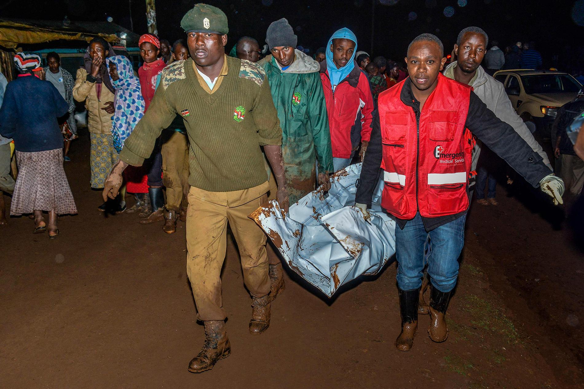 Räddningsarbetare tar hand om offer efter att en damm brustit i Nakaru provinsen i Kenya. 