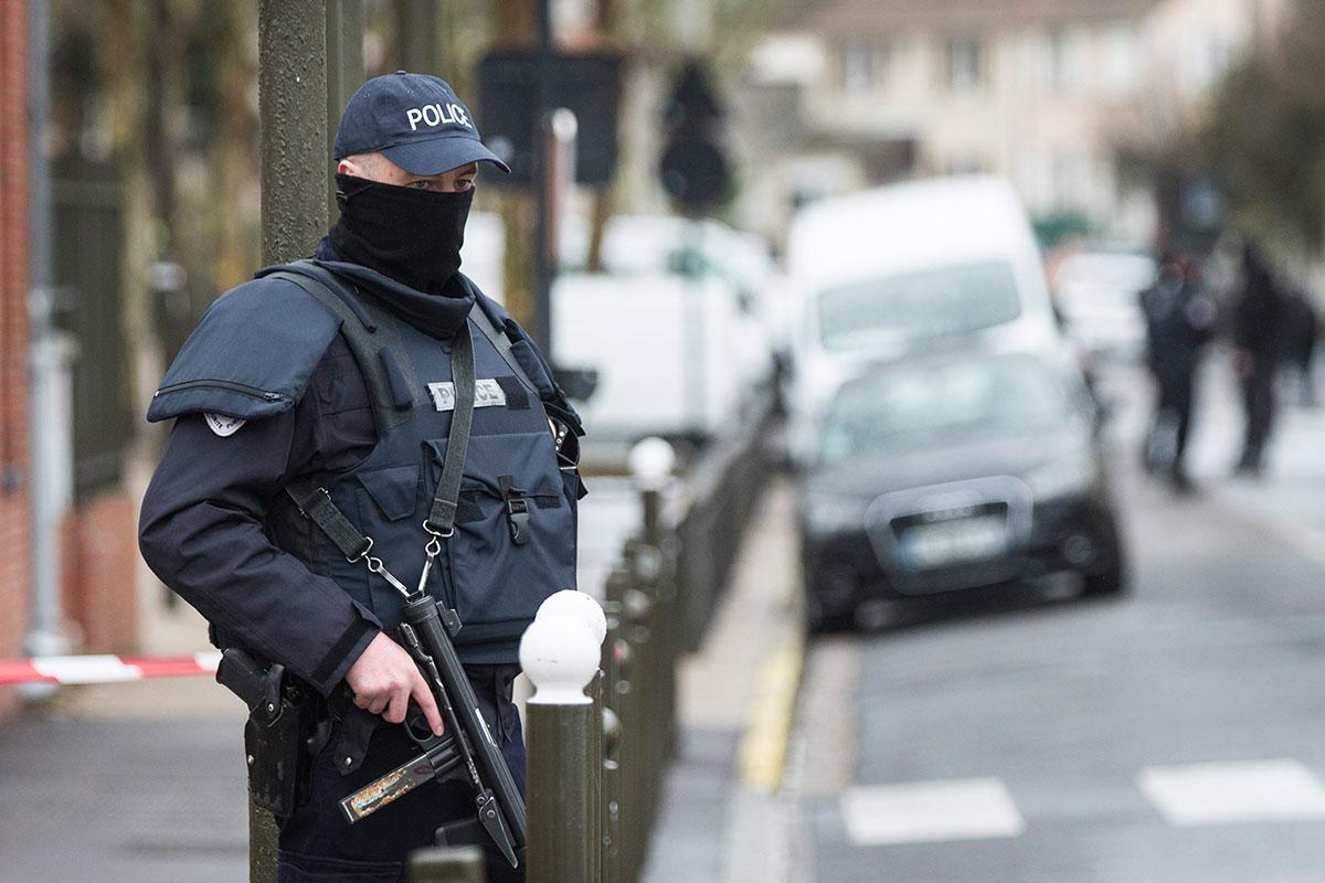En polis står utanför en byggnad under ett terrorinslag i Argentuill nära Paris 25 mars.