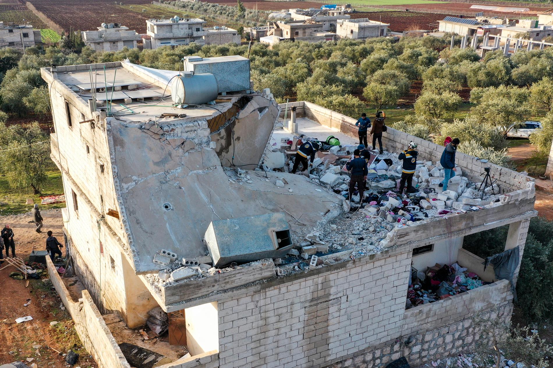 Människor undersöker ett förstört hus efter en amerikansk militäroperation i byn Atmeh i Idlibprovinsen. 