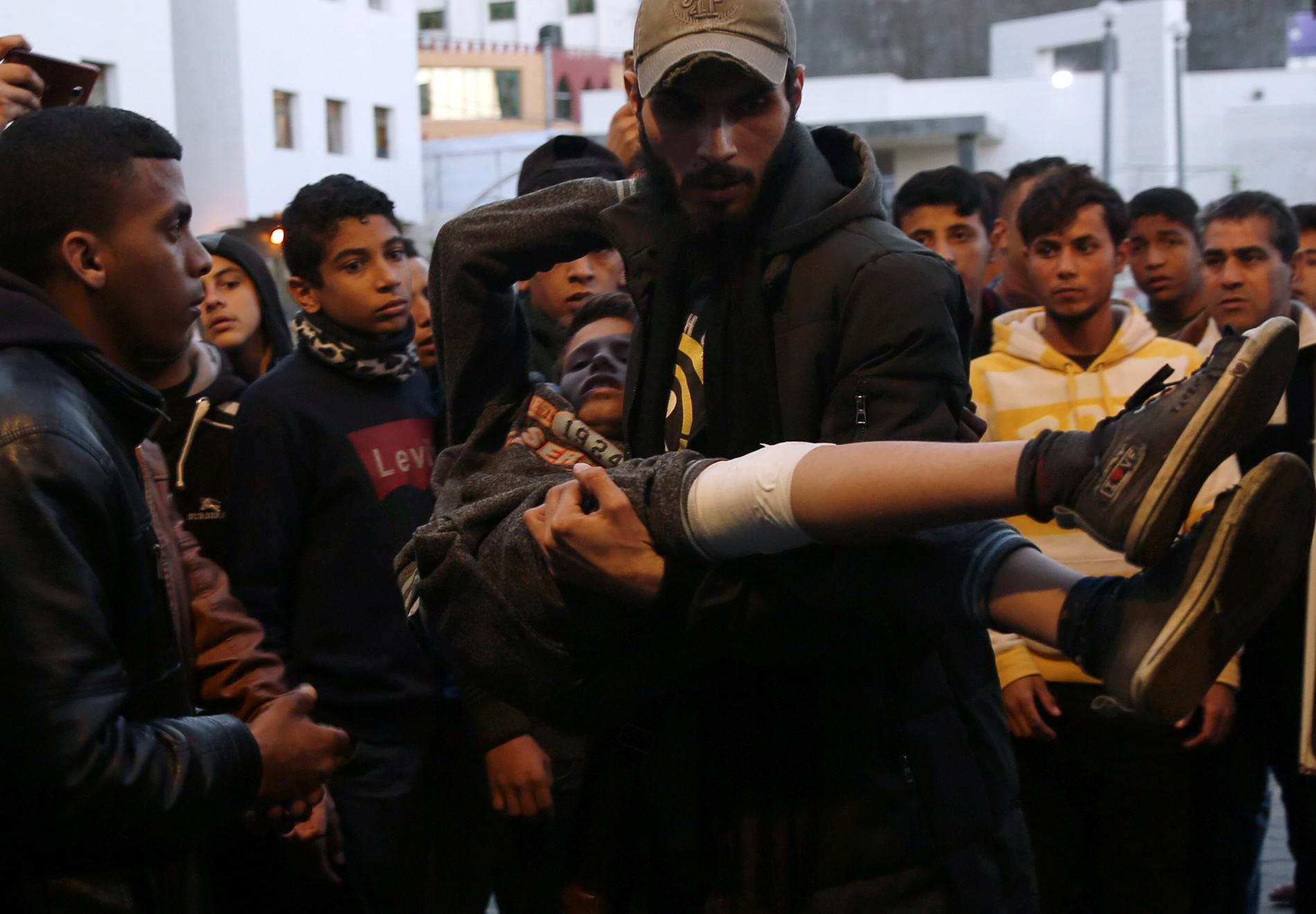 En man bär på en pojke som skottskadats i benet under fredagens protester i Gazaremsan.