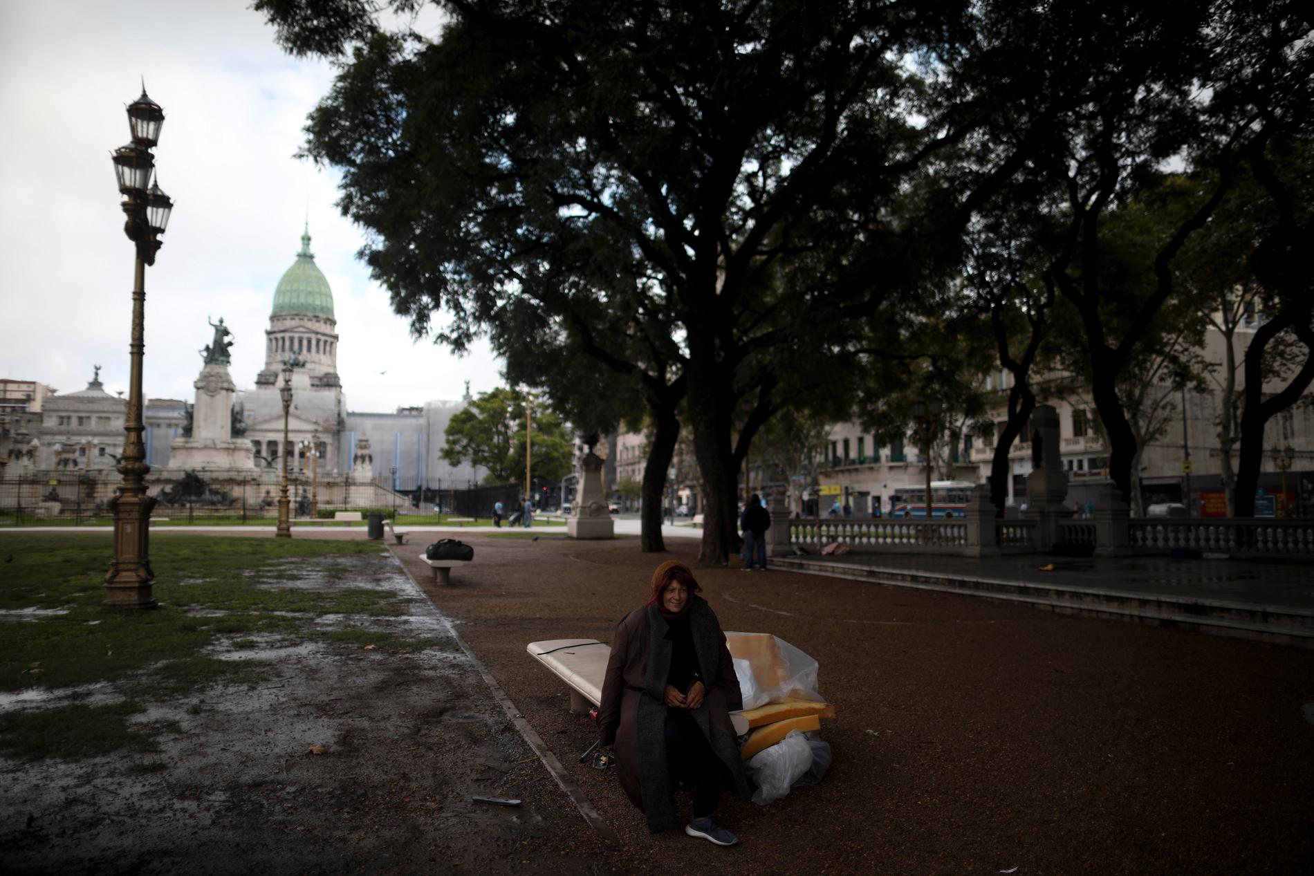 En kvinna sitter på en bänk utanför kongressen i Buenos Aires, Argentina. Få människor syns ute i huvudstaden då karantän införts.