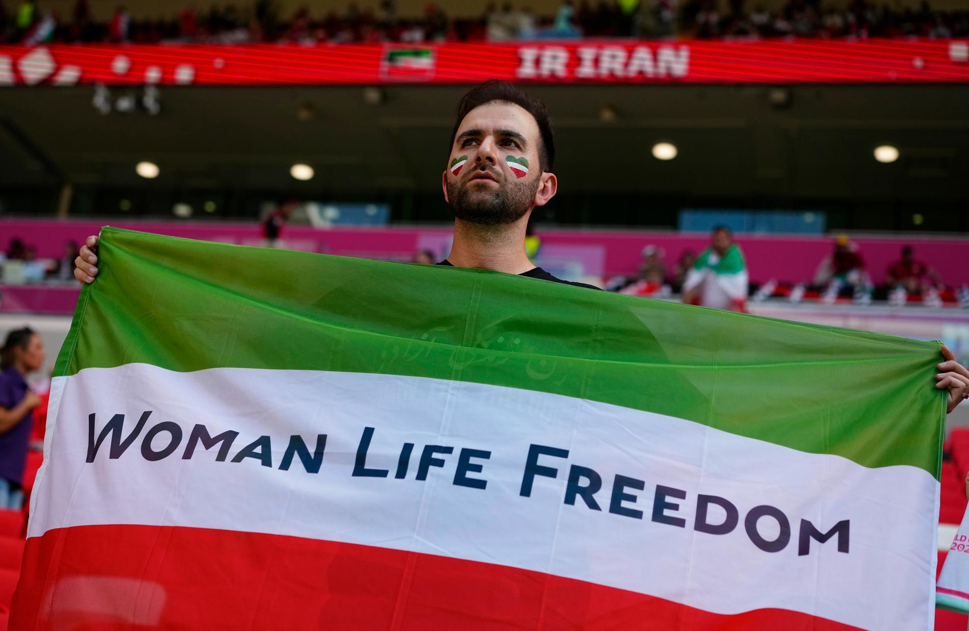 En iransk supporter håller upp en flagga med den iranska proteströrelsens slagord på läktaren.