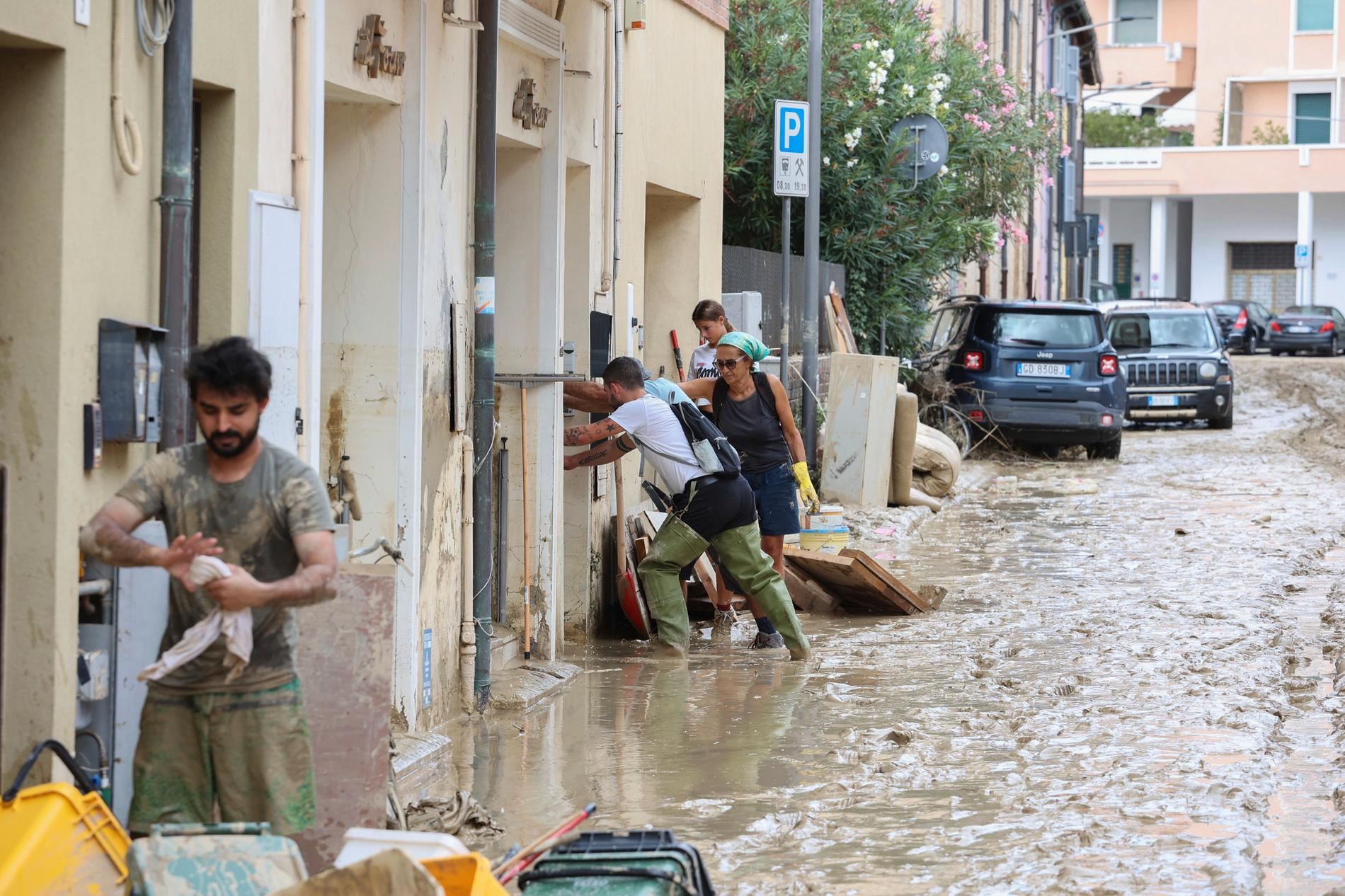Människor jobbar med att få bort lera ifrån staden Senigallia, Italien. 