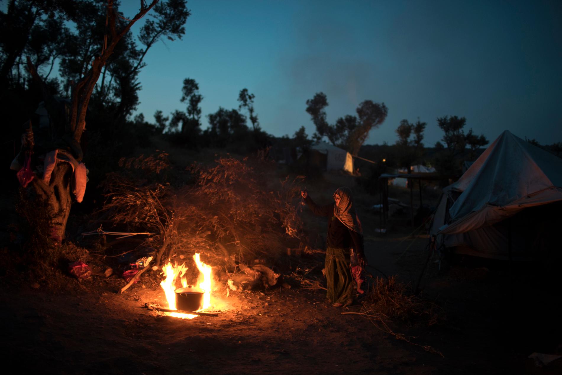 En syrisk kvinna lagar mat över öppen eld i ett provisoriskt läger som ligger utanför Moria på Lesbos. Arkivbild.