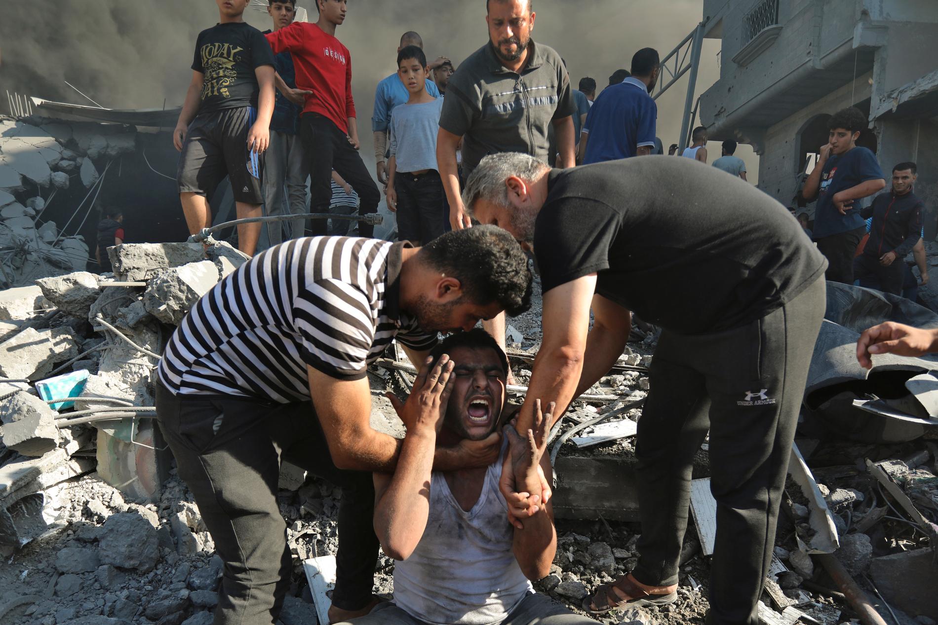 Palestinier tröstar en man som förlorat anhöriga efter israeliska flyganfall mot Gaza under söndagen.