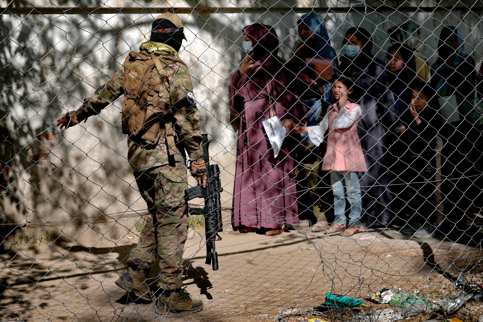 En taliban vaktar utanför passkontoret i Kabul i april i år.
