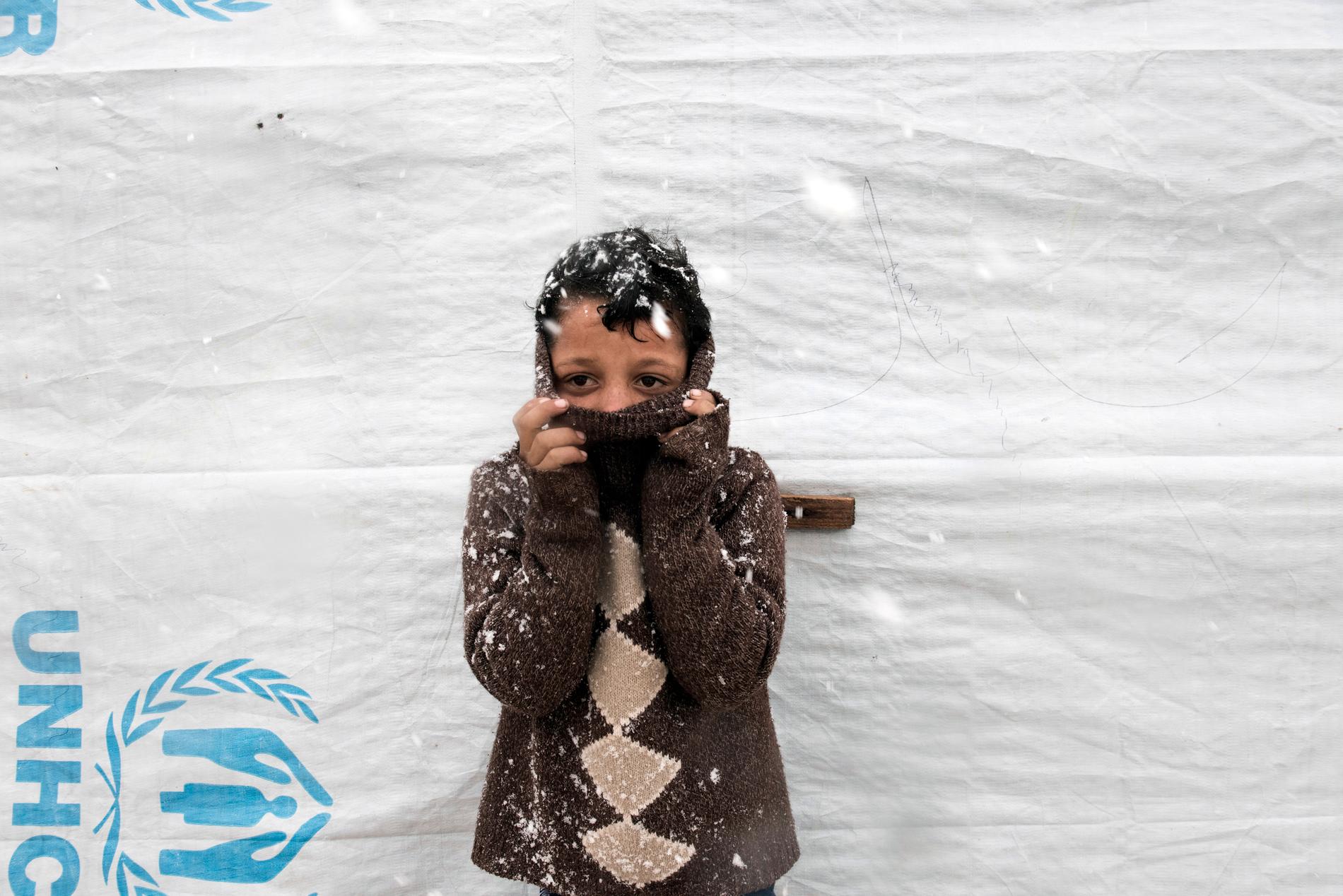 Omar, 11, saknar vantar och mössa.  Han gömmer sitt ansikte i den tjocka tröjan för att undvika kylan. I Bekaadalen kan snön och minusgraderna stoppa de dåligt klädda barnen från att gå till skolan.