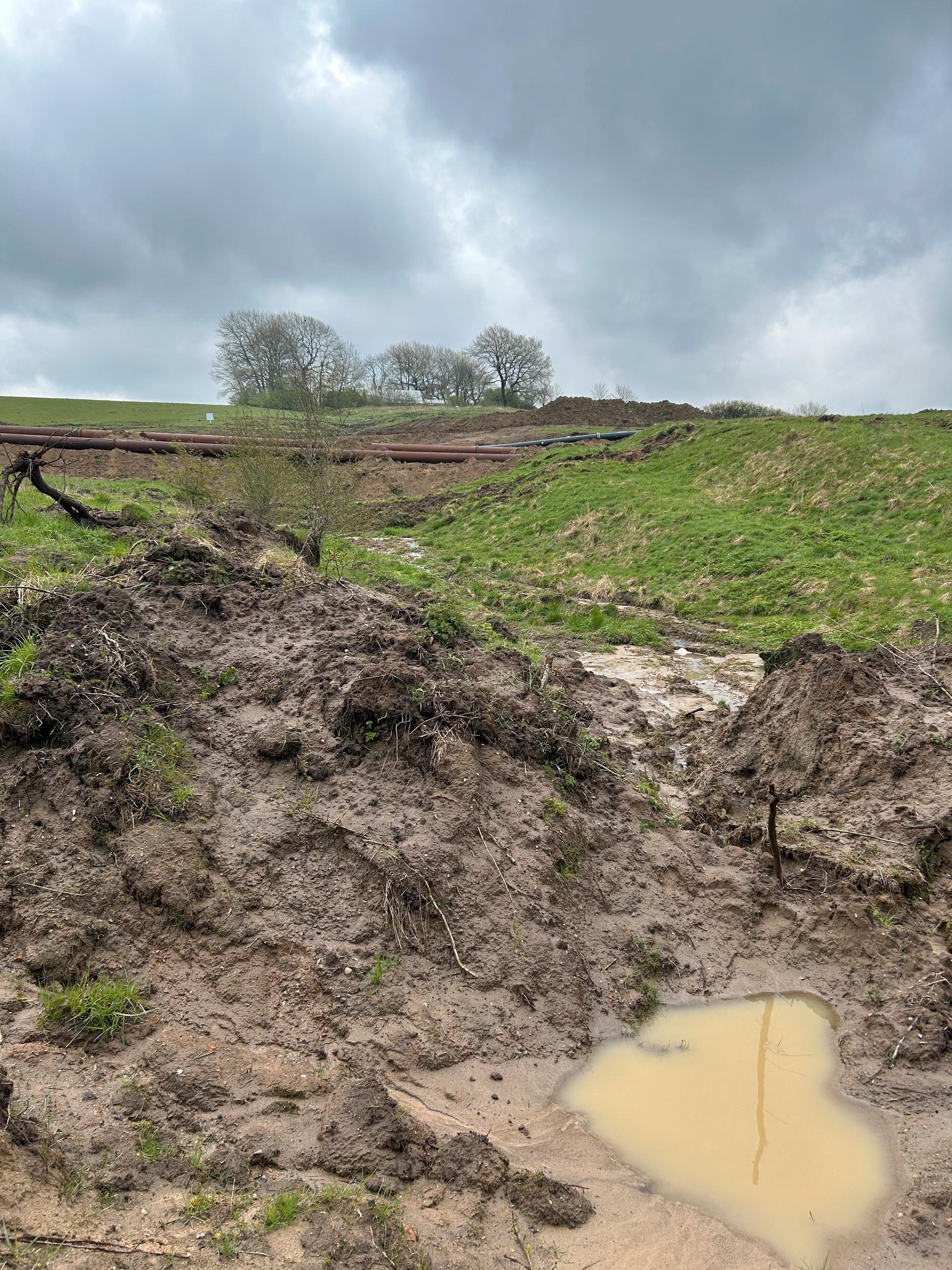 Bonden intill tvingades flytta sina får när kommunen akut tvingades leda in ån genom stora rör delar av sträckningen för att undvika massiva översvämningar. Rören syns i bakgrunden.