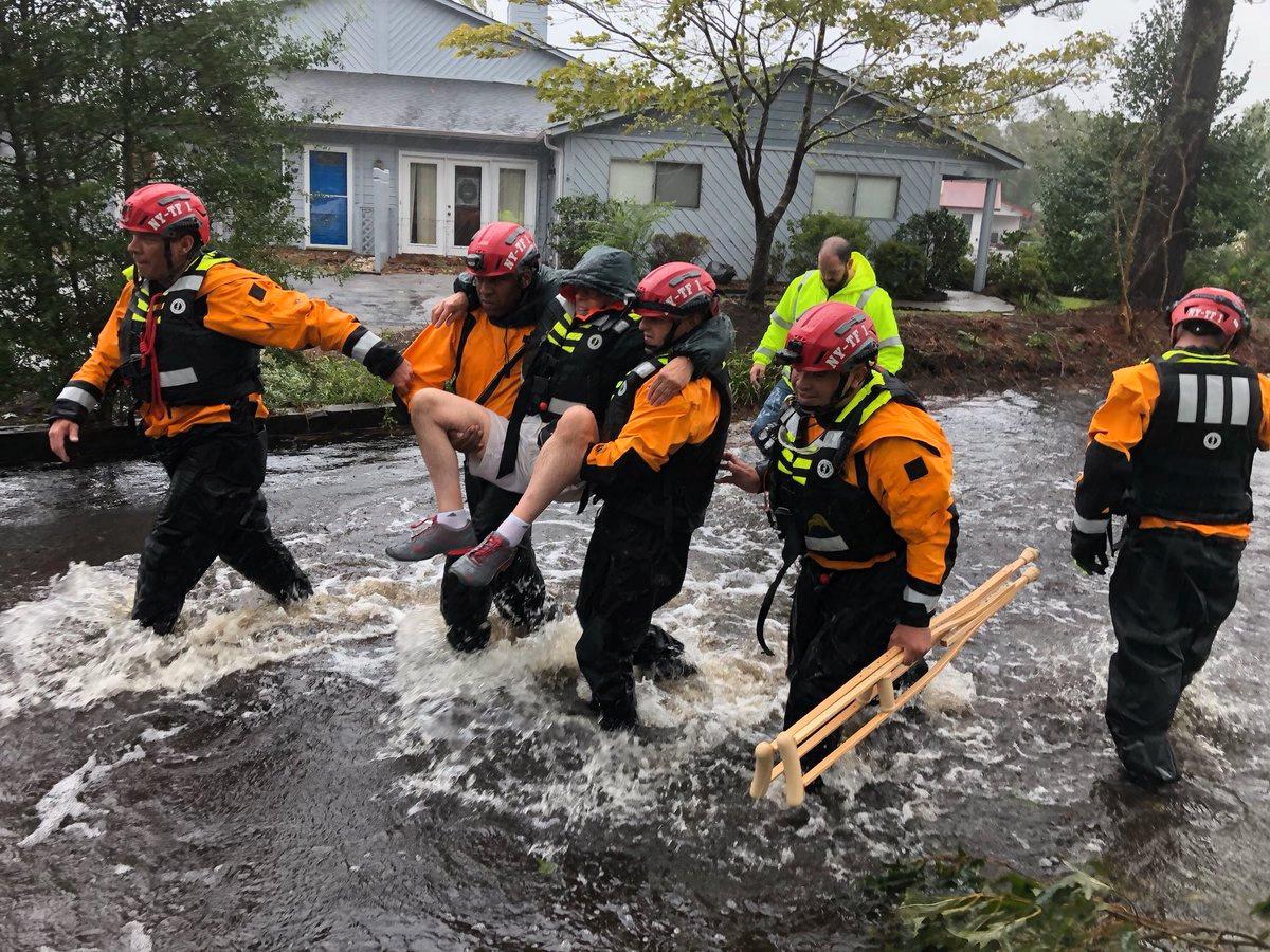 Räddningsarbetare från New York tar hand om en man på de översvämmade gatorna i River Bend, North Carolina.