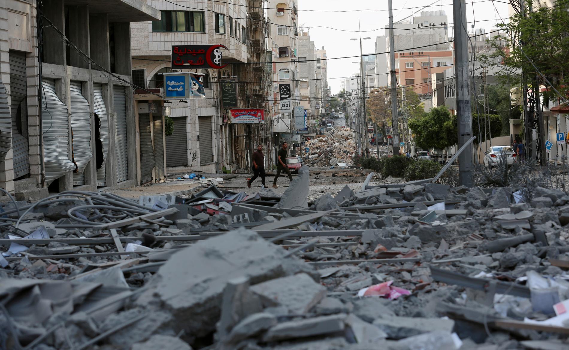 Människor inspekterar resterna av en bombad kommersiell by7ggnad och en vårdklinik i staden Gaza.