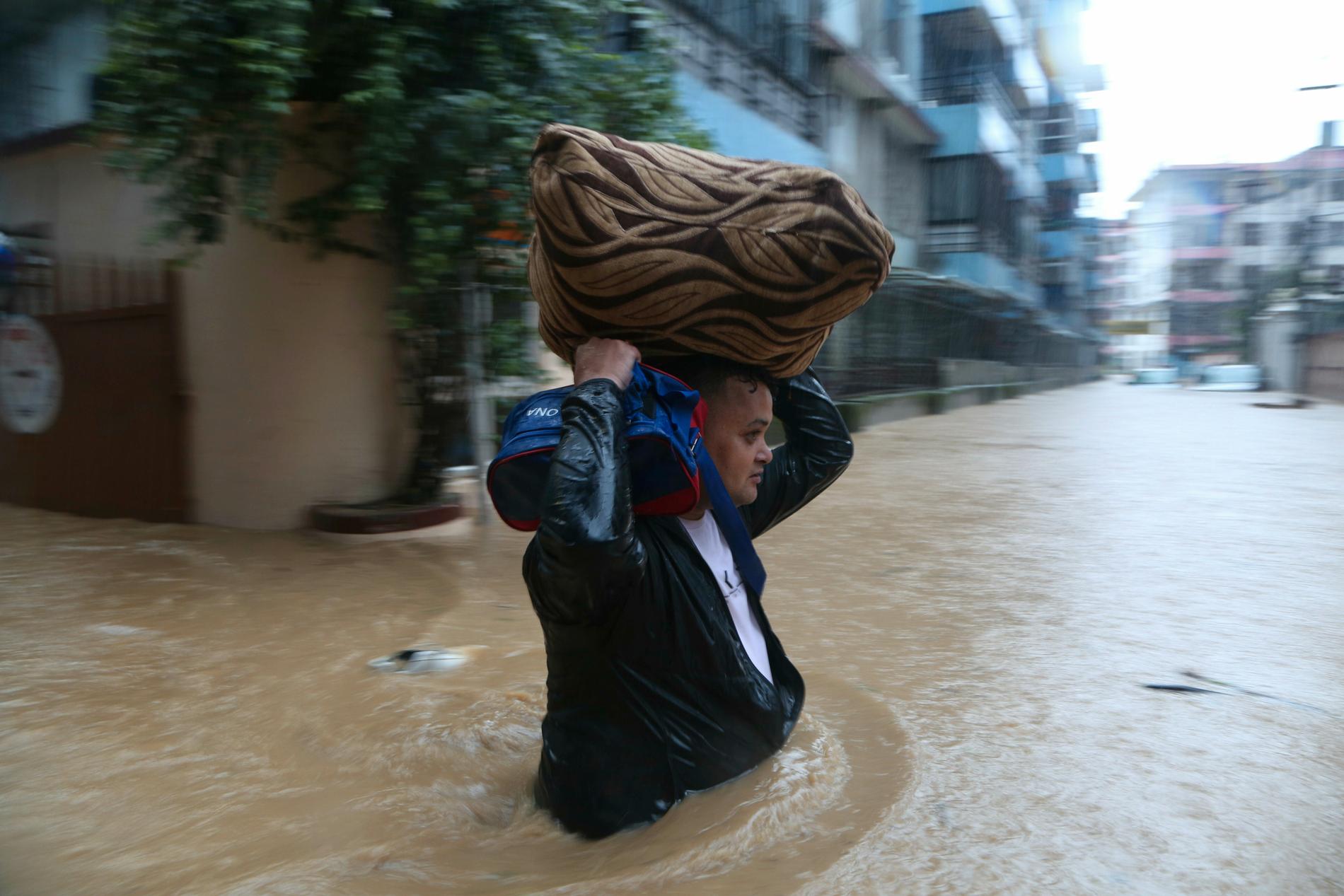 En nepalesisk man i fredags, då han vadade på en översvämmad gata i Katmandu med sina tillhörigheter.