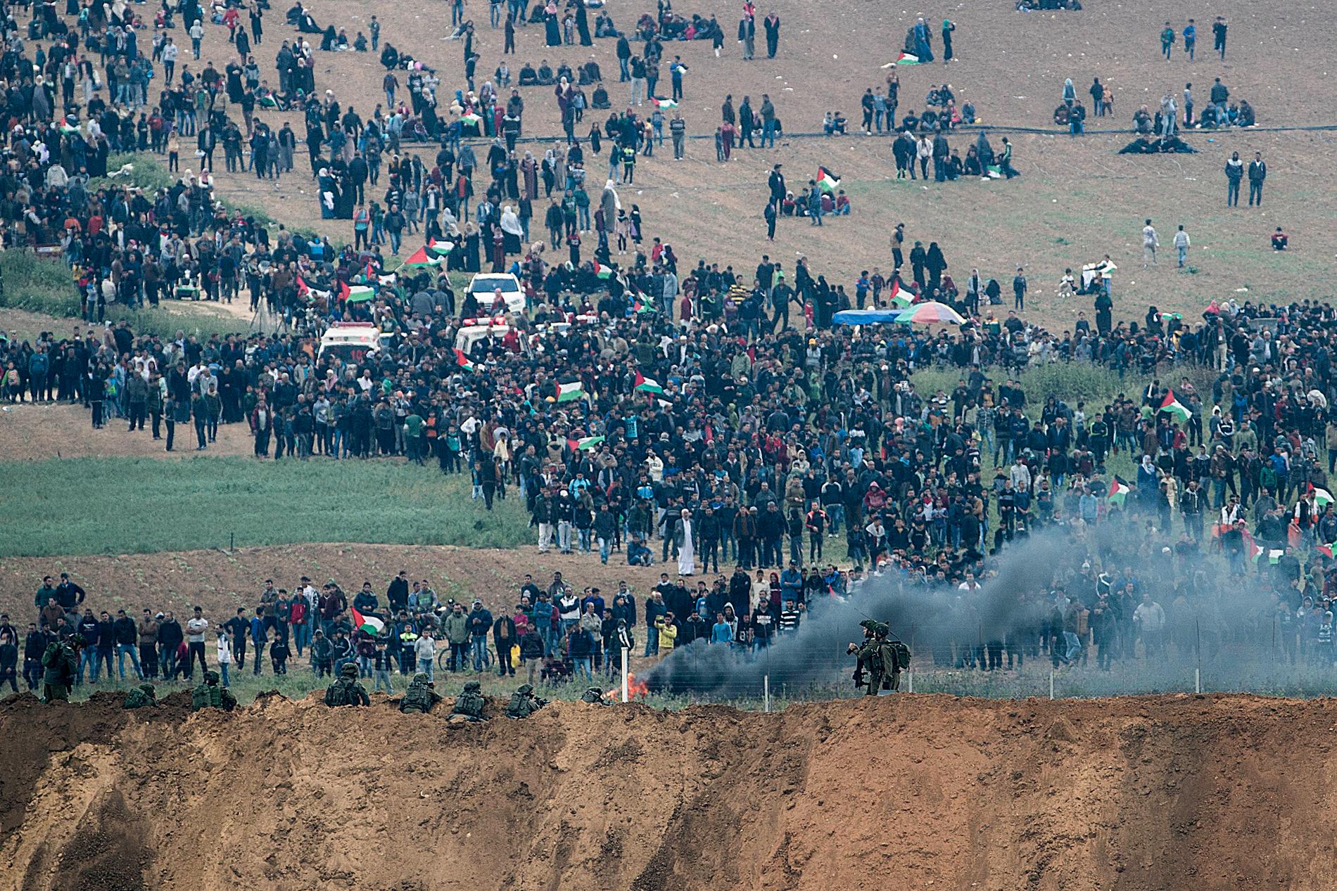 Palestinska demonstranter under fredagens protester vid Gazagränsen. I förgrunden ses israeliska soldater.