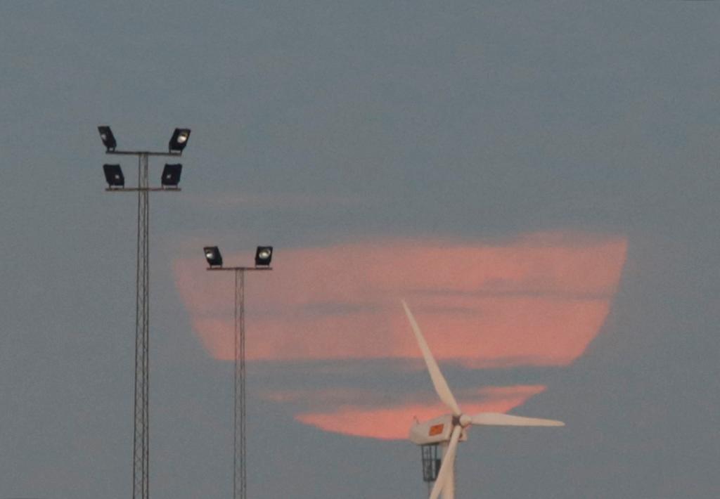 Supermånen går upp bakom ett vindkraftverk i hamnen i Malmö på söndagskvällen.