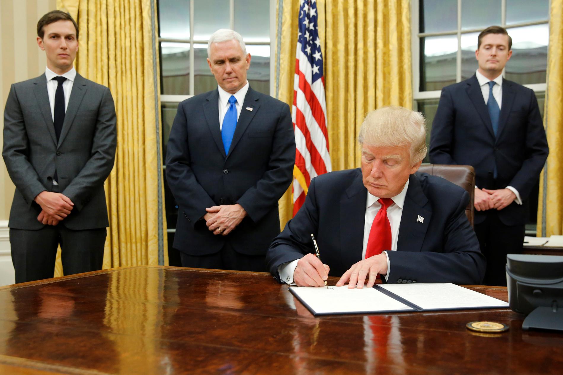 Donald Trump skriver under ett dekret, flankerad av bland andra Jared Kushner.