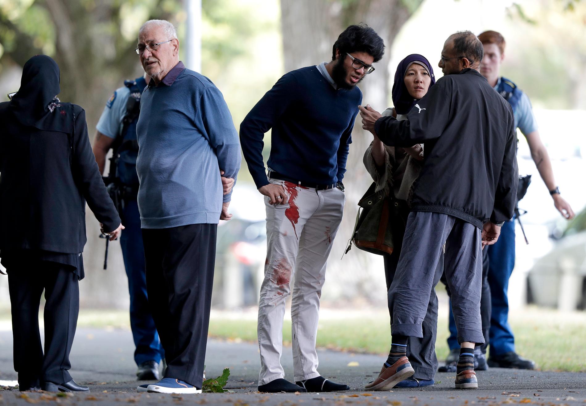 Människor står utanför en av de moskéer som attackerats i Christchurch på fredagen.