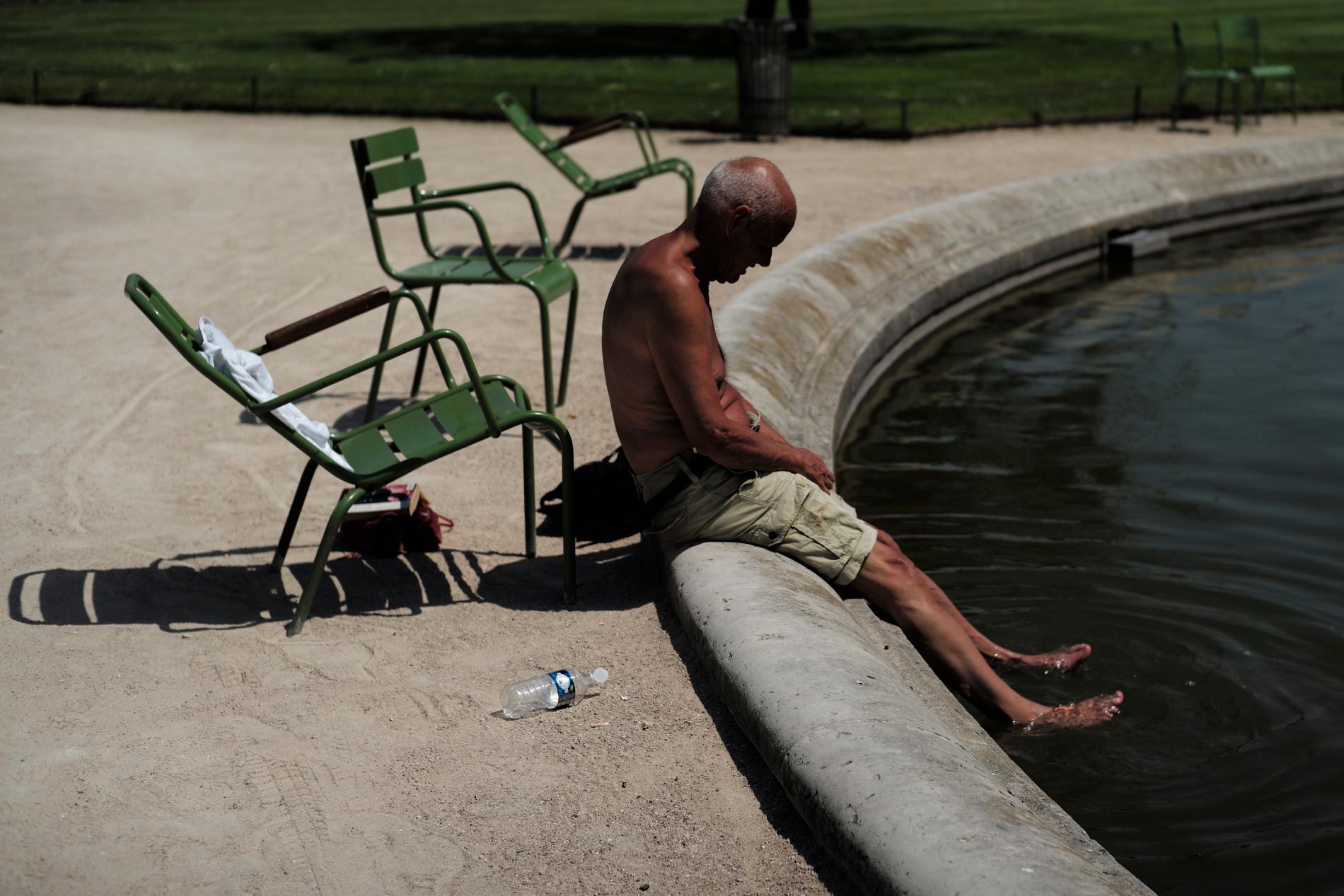 En man svalkar fötterna i en fontän i Tuilerierna i Paris på torsdagen.