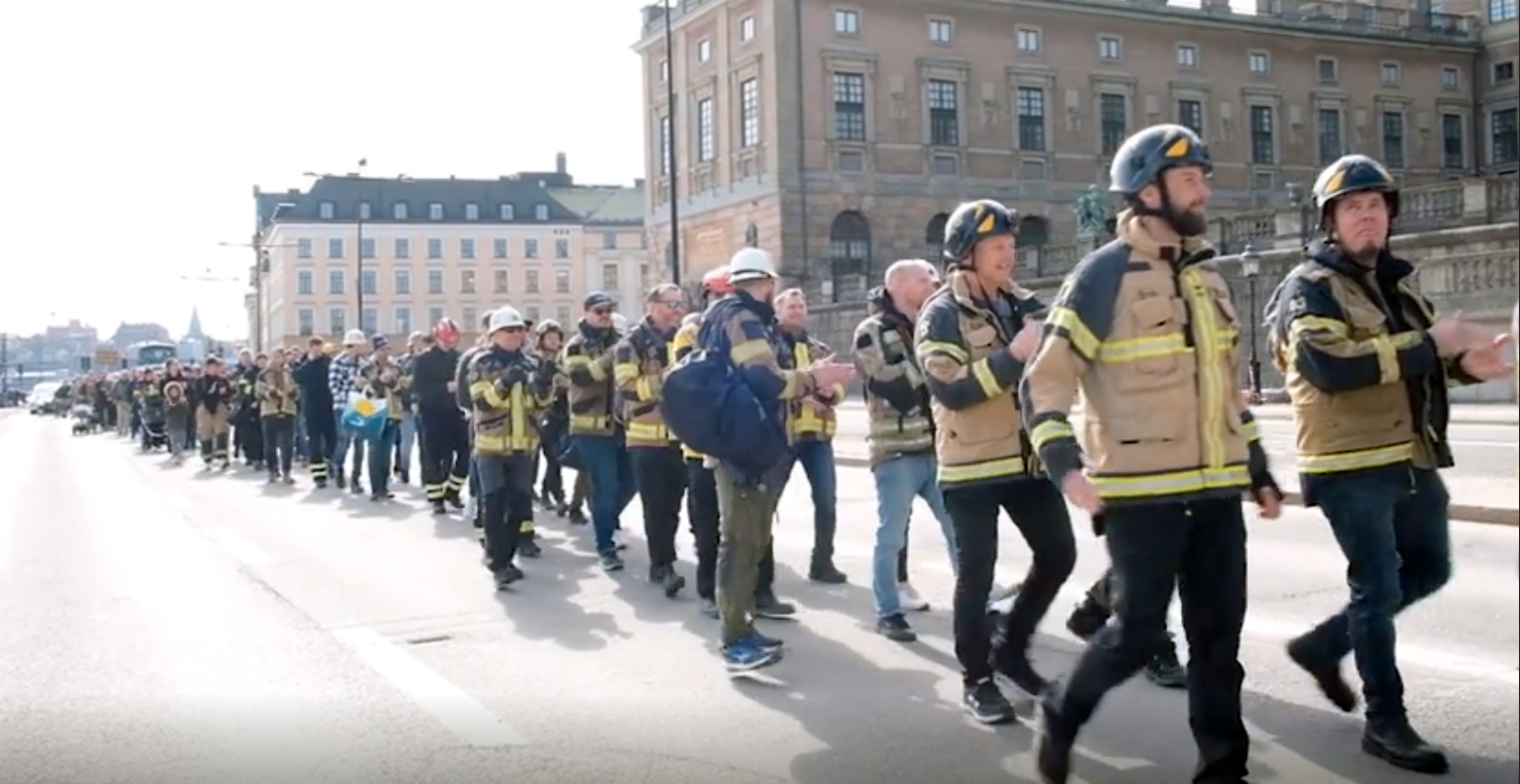 Brandmän i protesttåg utanför Stockholms slott. 
