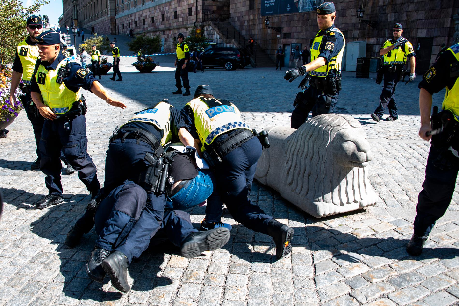 En motdemonstrant brottas ner vid en koranbränning i Stockholm.